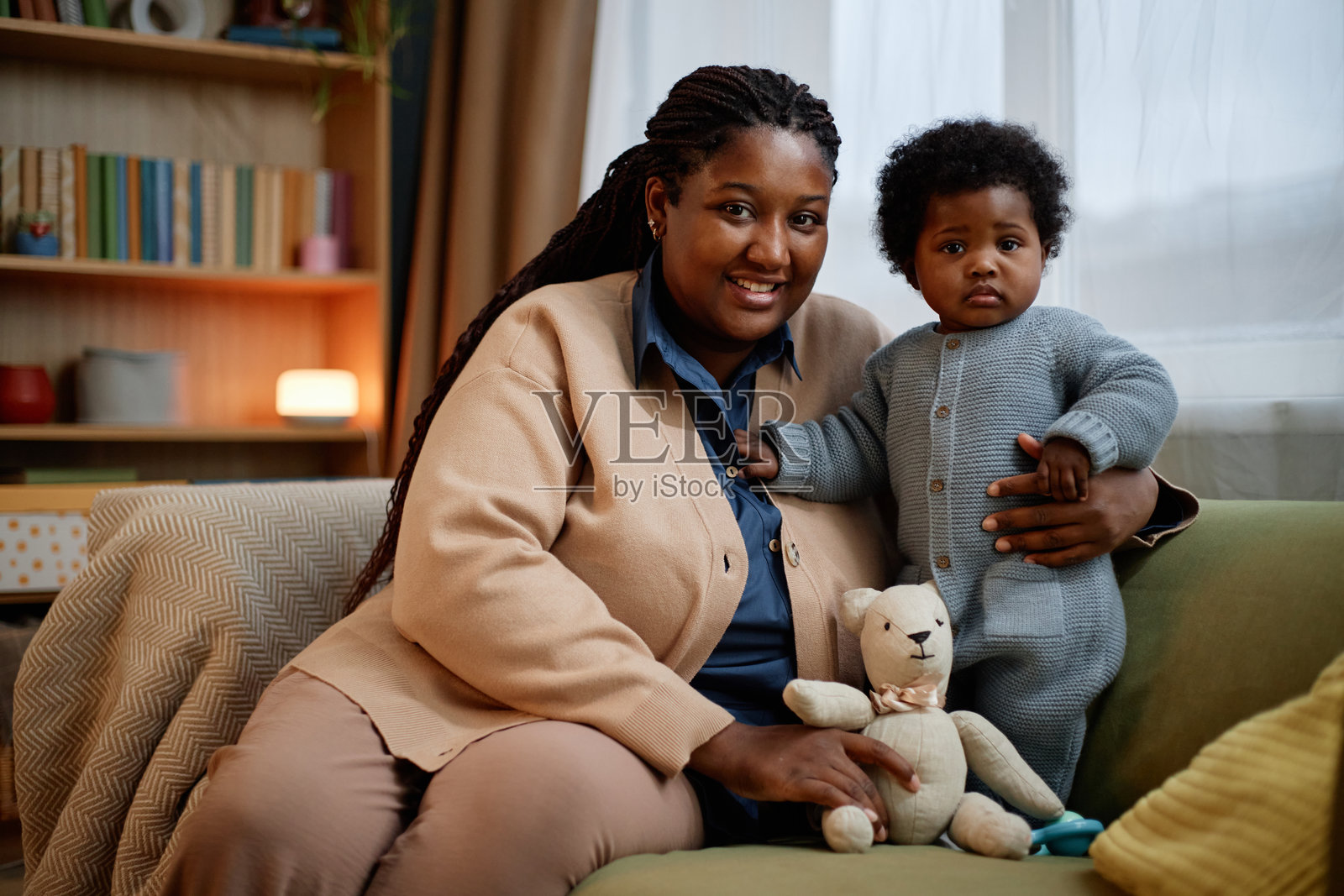 快乐的黑人母亲与女儿在室内沙发上拥抱合影照片摄影图片