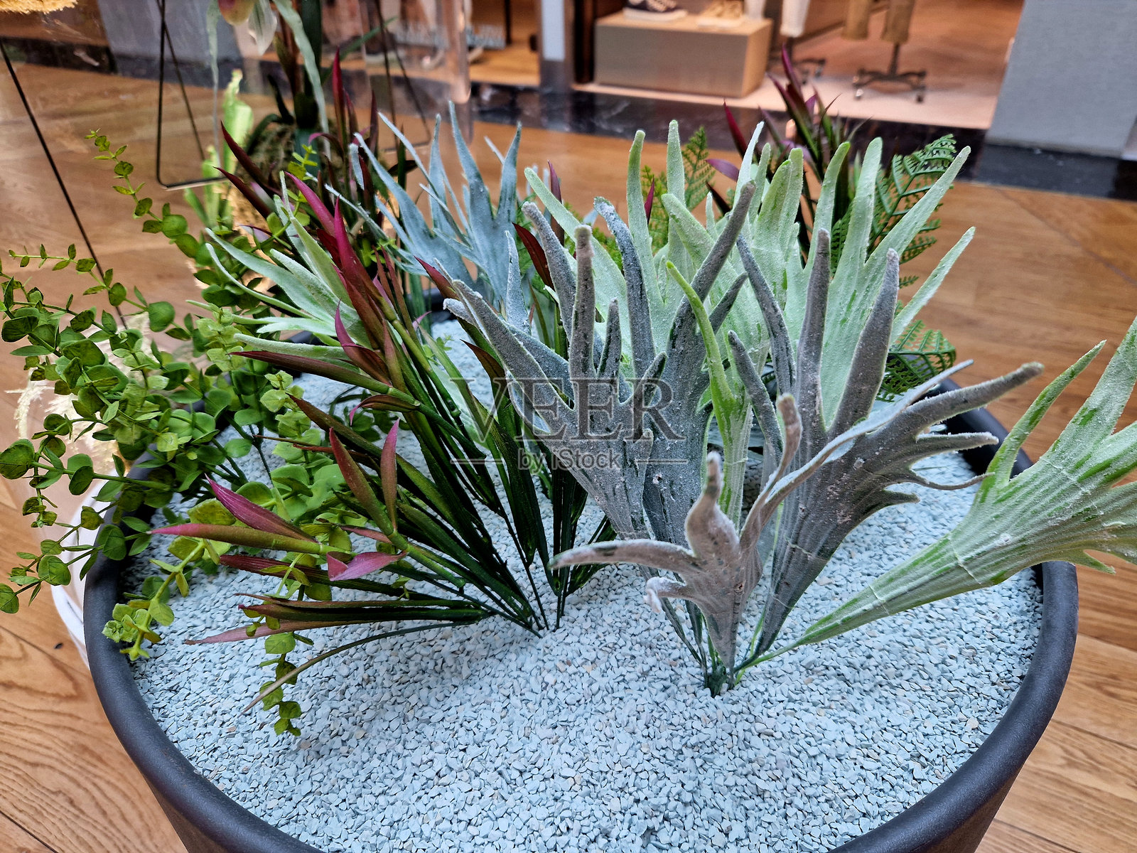 花盆中粘附的树枝和叶子，塑料仿真室内植物，外观逼真。位于豪华大堂，红色地板。银行、天井、办公室和购物中心。照片摄影图片