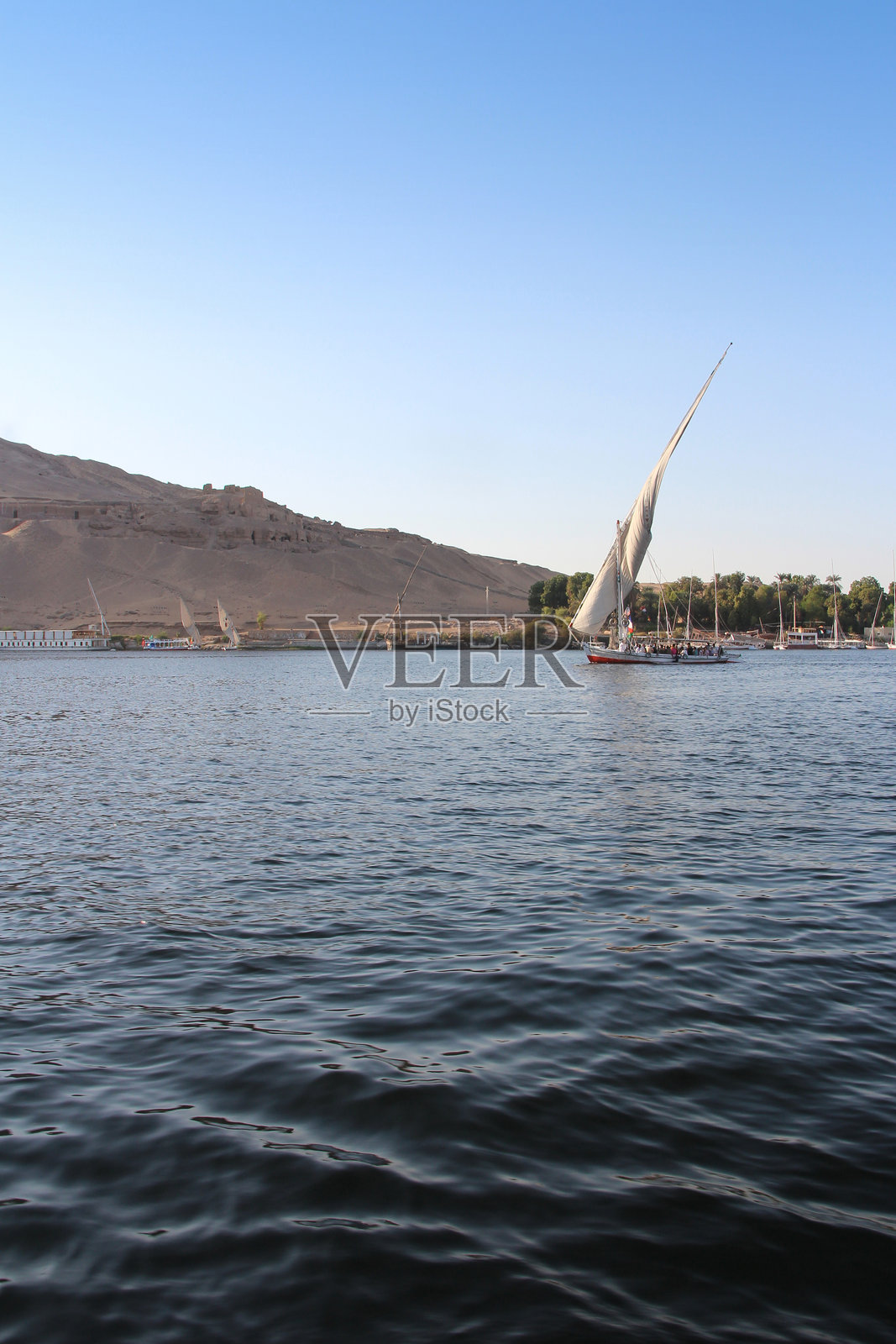 日落时分在尼罗河上航行的费卢卡帆船照片摄影图片