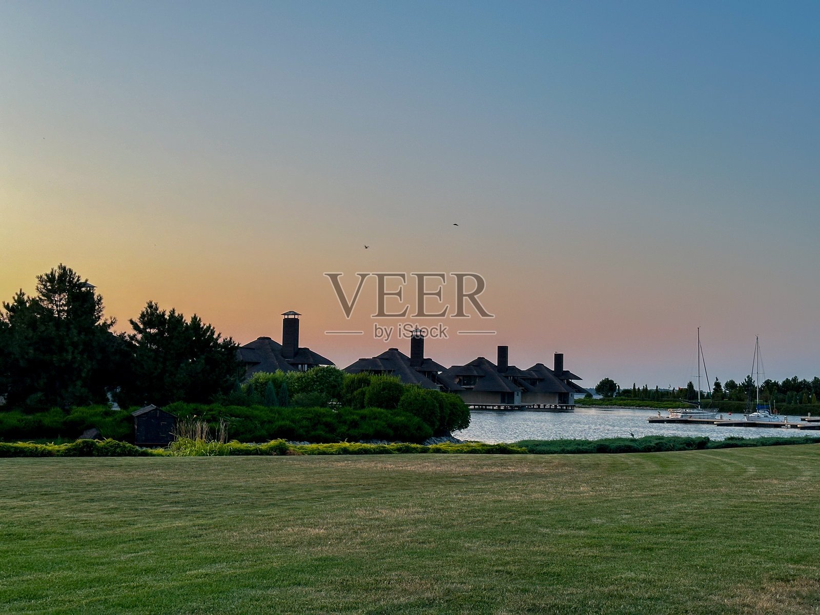 日落时分水面上的小房子照片摄影图片