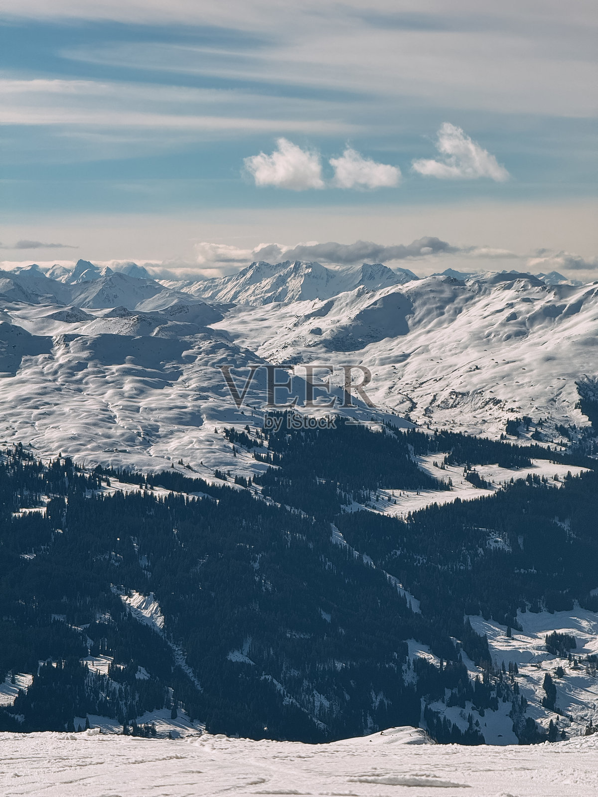 雄伟的雪山阿尔卑斯山脉耸立在被雪覆盖的山谷上，天空布满云彩。照片摄影图片