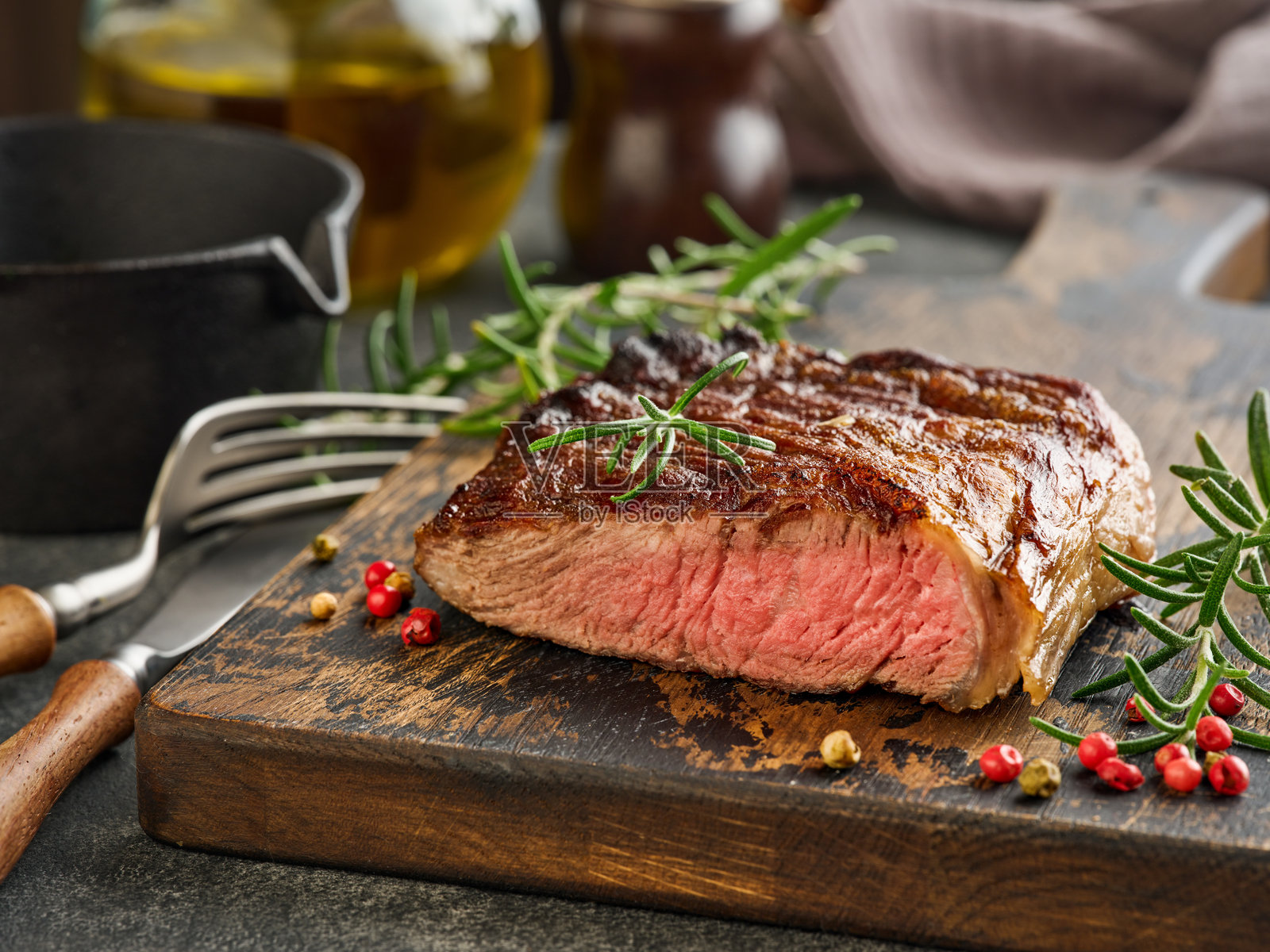 黑色盘子上的中等生牛排，配有餐具，放在黑色石桌上，留有充足的空白空间。深色背景。俯视图。空白空间。照片摄影图片