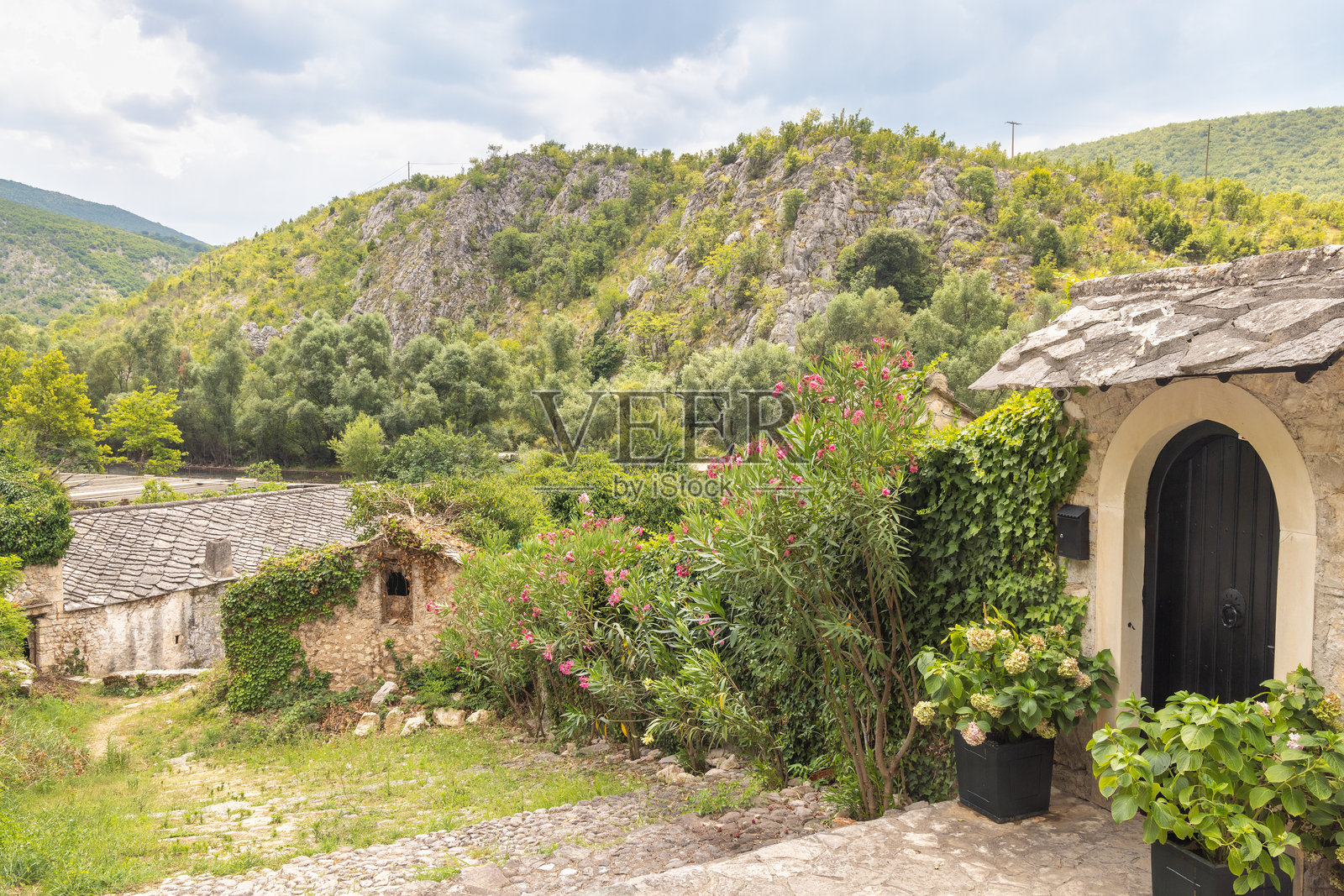 波斯尼亚和黑塞哥维那布拉加伊村的古老石屋。石头建筑依偎在自然中，背后是岩石山坡。这个场景宁静，建筑与环境融为一体。照片摄影图片