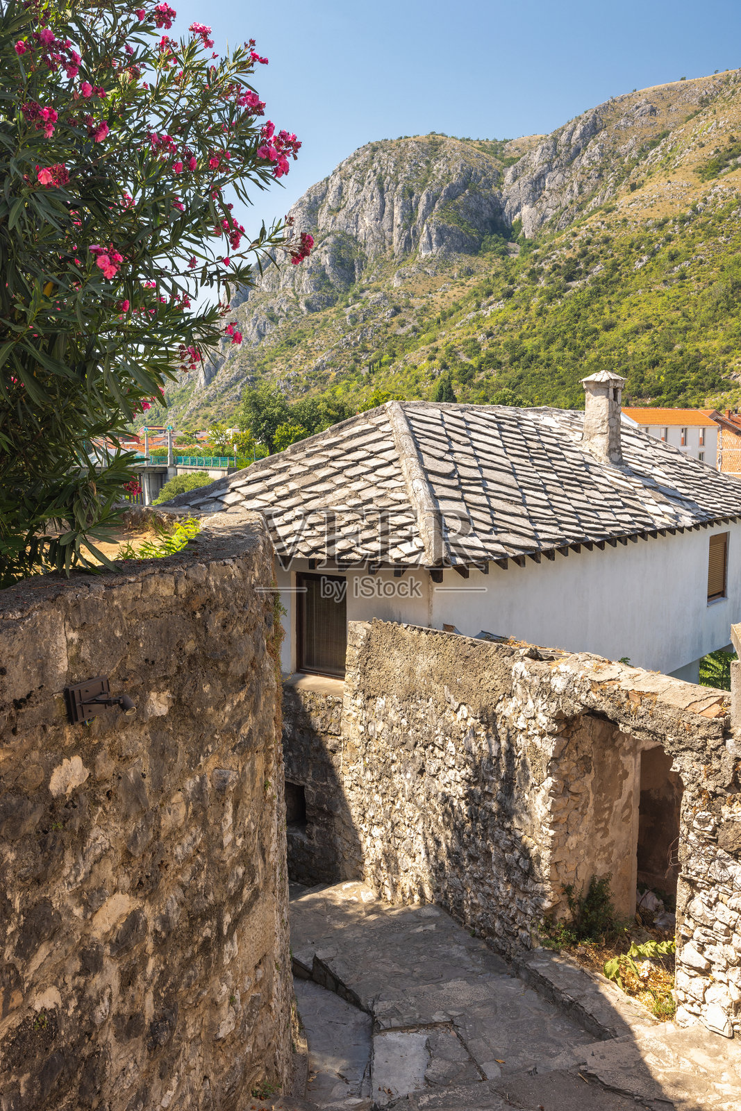 波斯尼亚和黑塞哥维那的莫斯塔尔，历史悠久的城镇。风景如画的欧洲小镇：石墙和建筑，背后是清澈天空下的山脉。迷人的古老建筑风格。照片摄影图片