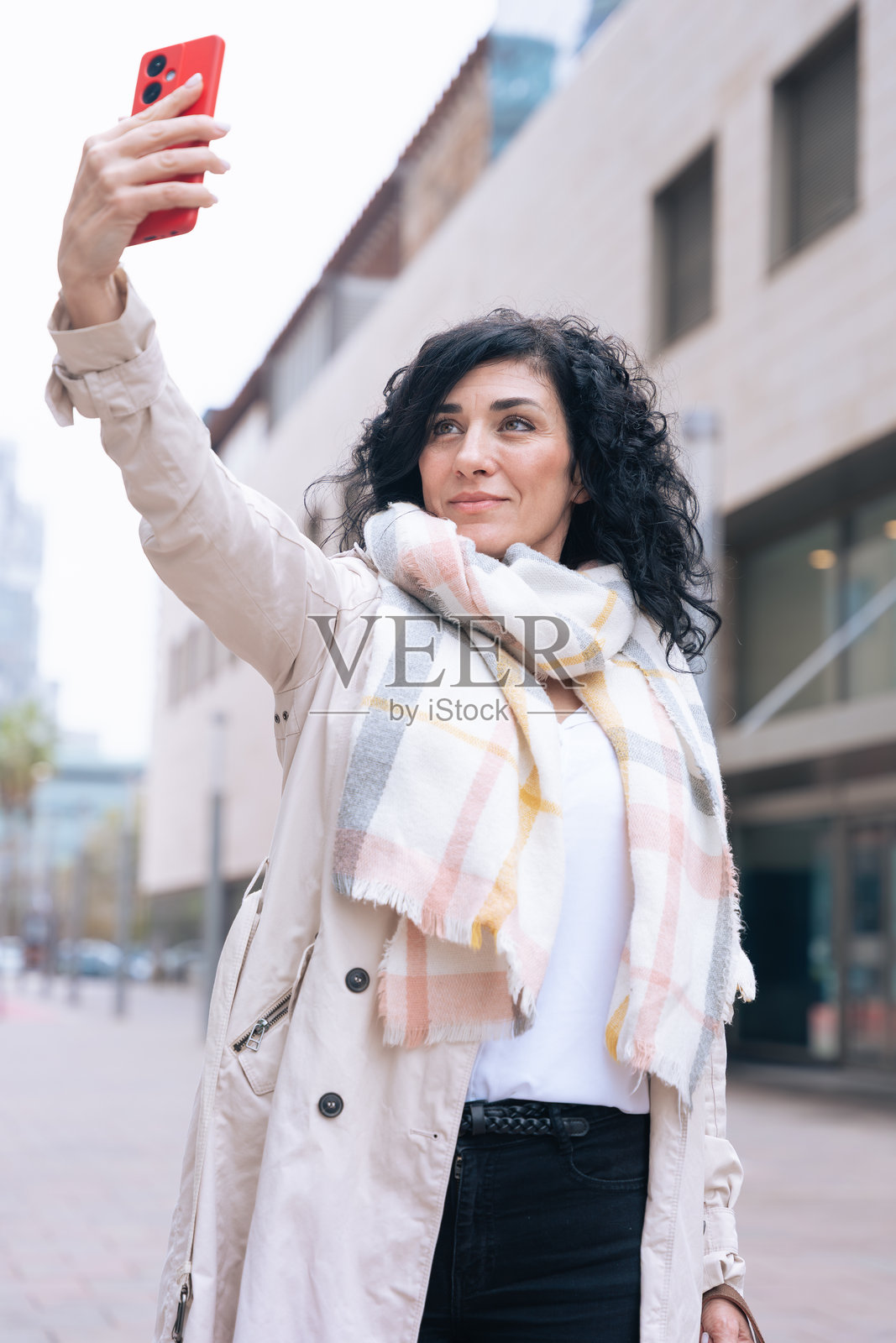 自信的女性在现代城市街道户外用智能手机自拍照片摄影图片