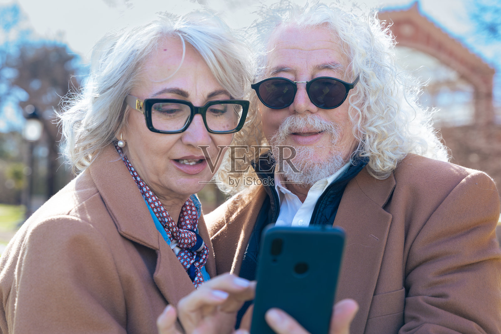 白人老年夫妇在户外使用手机浏览社交媒体应用照片摄影图片