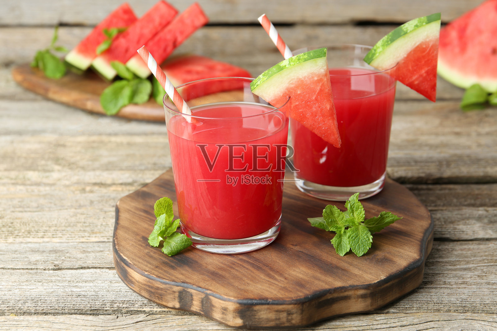 美味的西瓜饮料装在玻璃杯中，旁边有新鲜水果和薄荷，放在木桌上。照片摄影图片