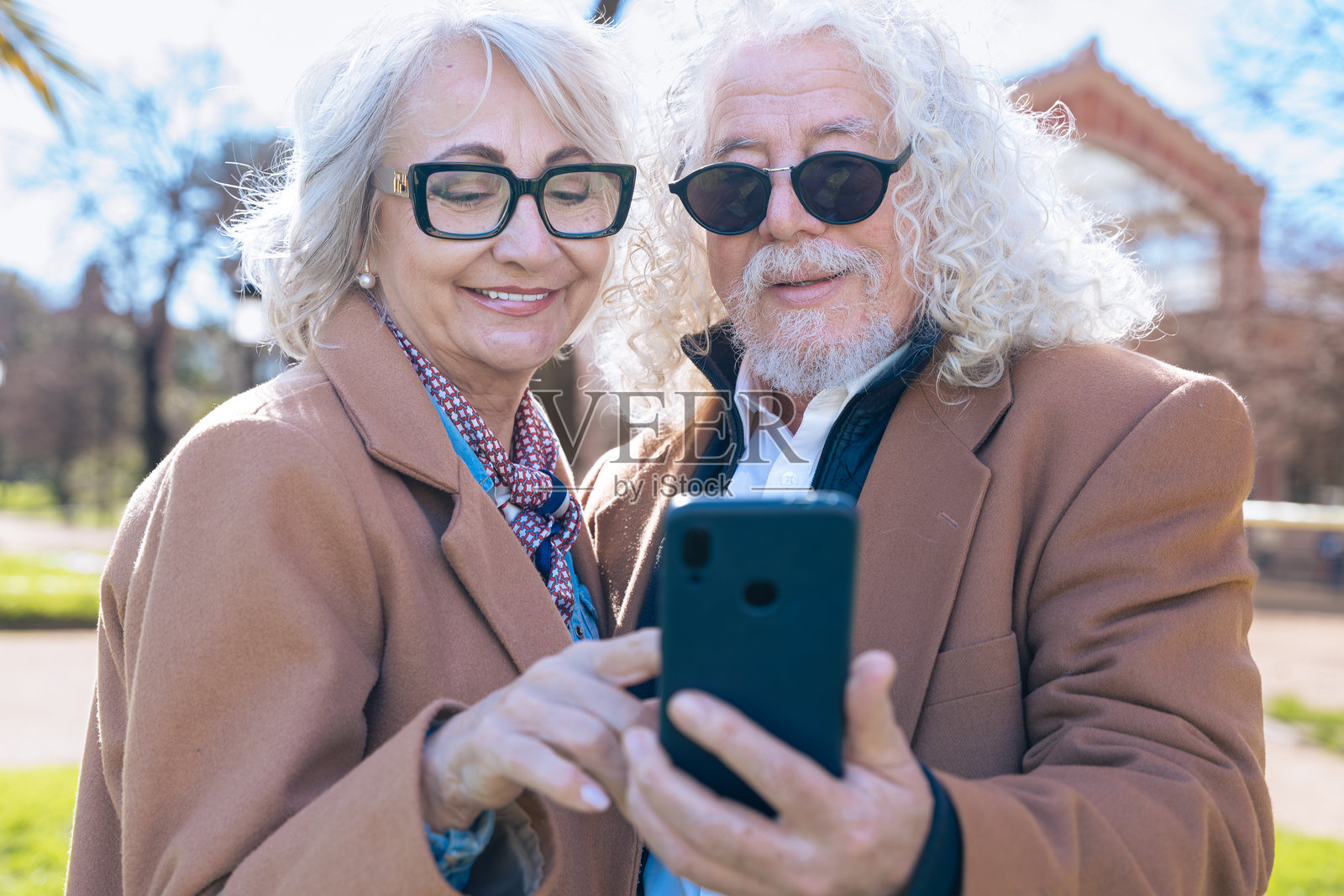 白人老年夫妇在户外使用手机浏览社交媒体应用程序照片摄影图片