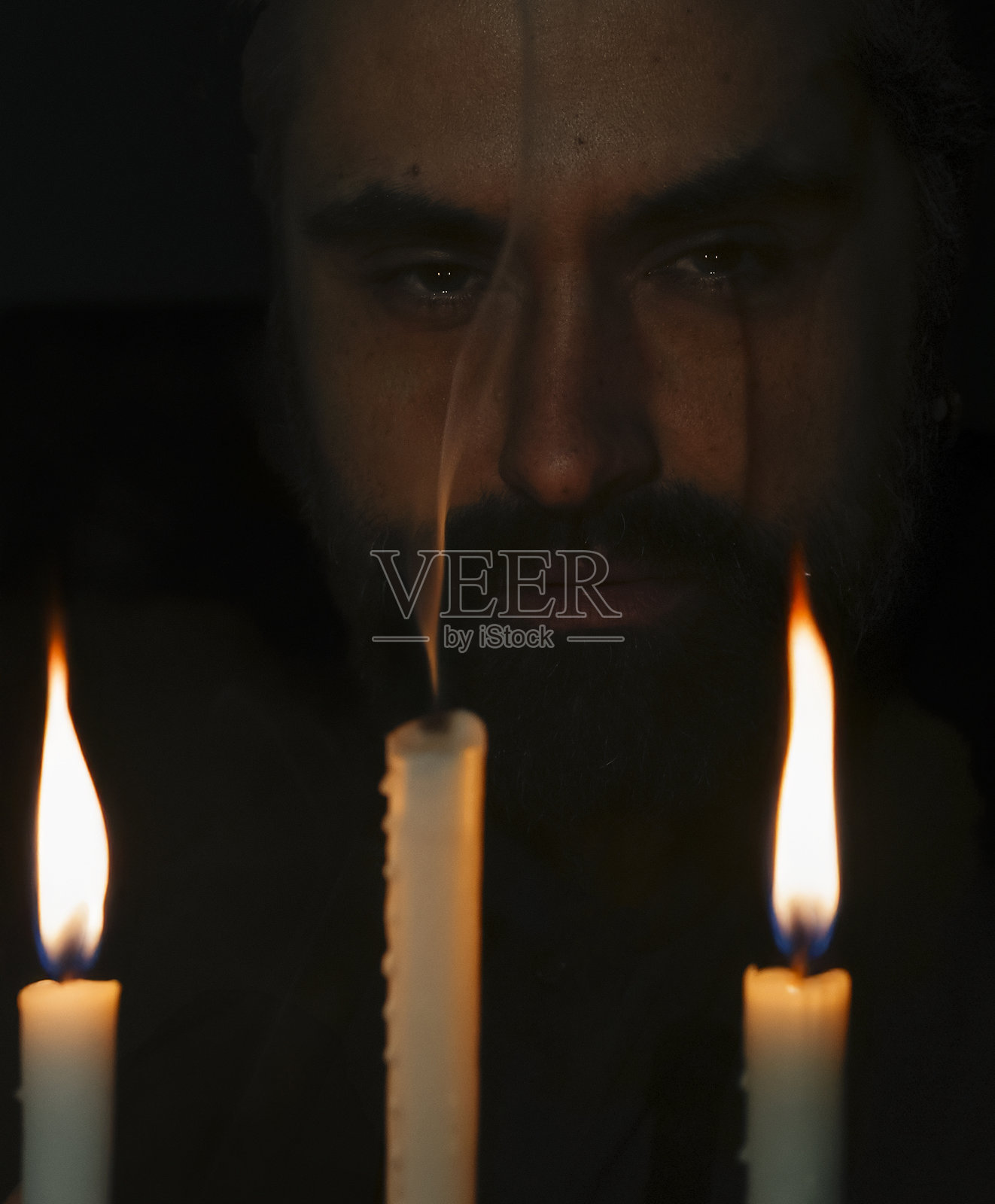 低光环境中燃烧蜡烛的强烈凝视。竖版照片照片摄影图片