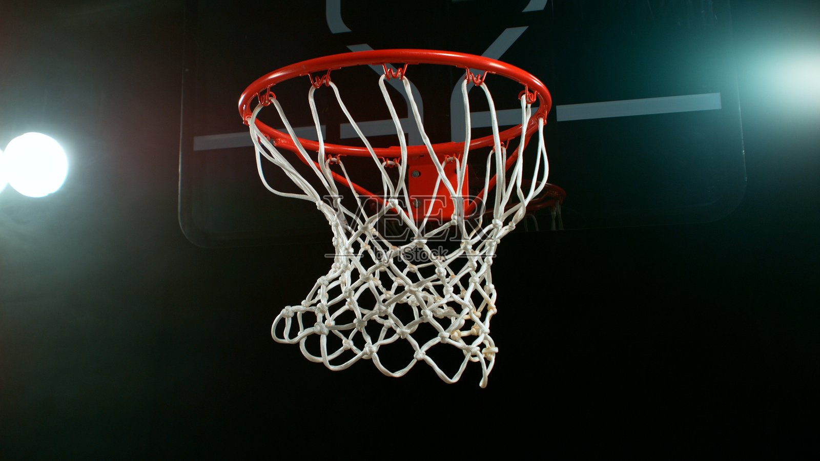 黑色背景下的篮球飞入篮筐照片摄影图片