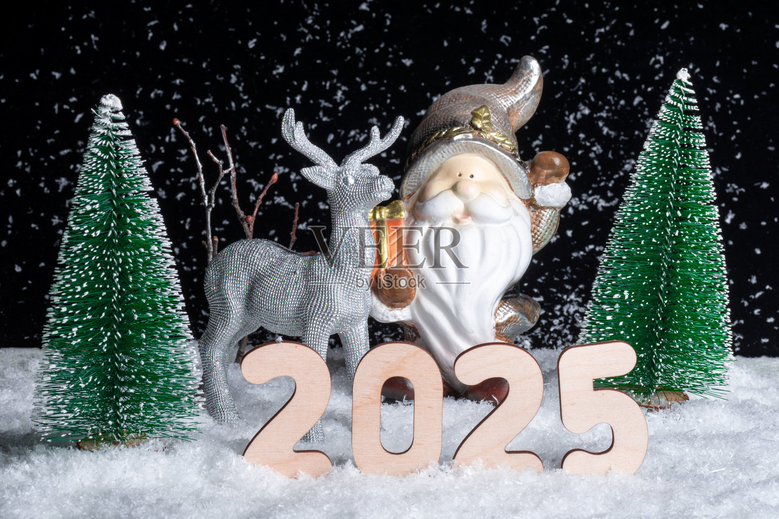 2025年除夕夜。一只闪亮的银色玩具鹿拉着装满礼物的圣诞老人雪橇穿过雪-covered森林。照片摄影图片