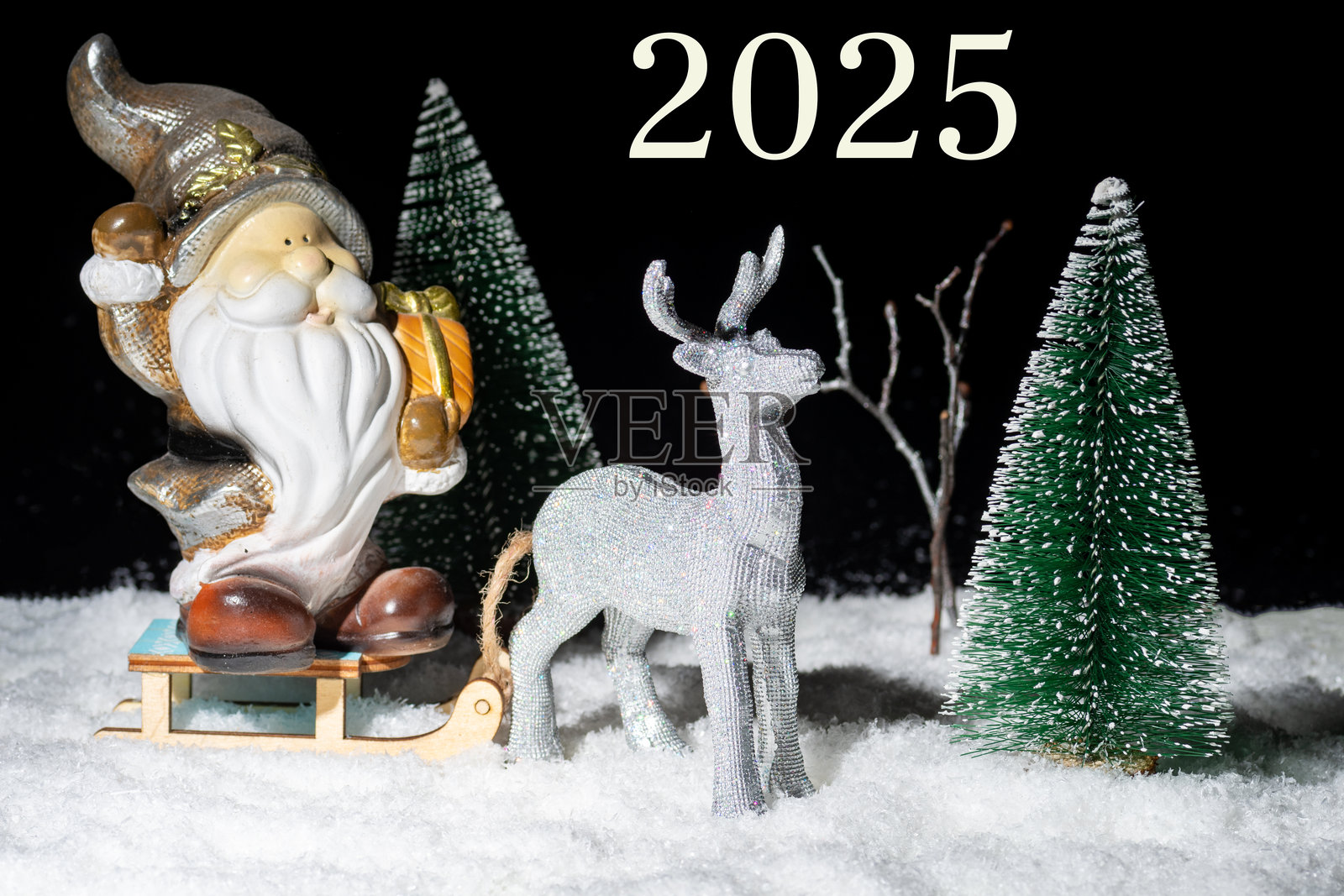 2025年除夕夜。一只闪亮的银色玩具鹿拉着装满礼物的圣诞老人雪橇穿过雪-covered森林。照片摄影图片