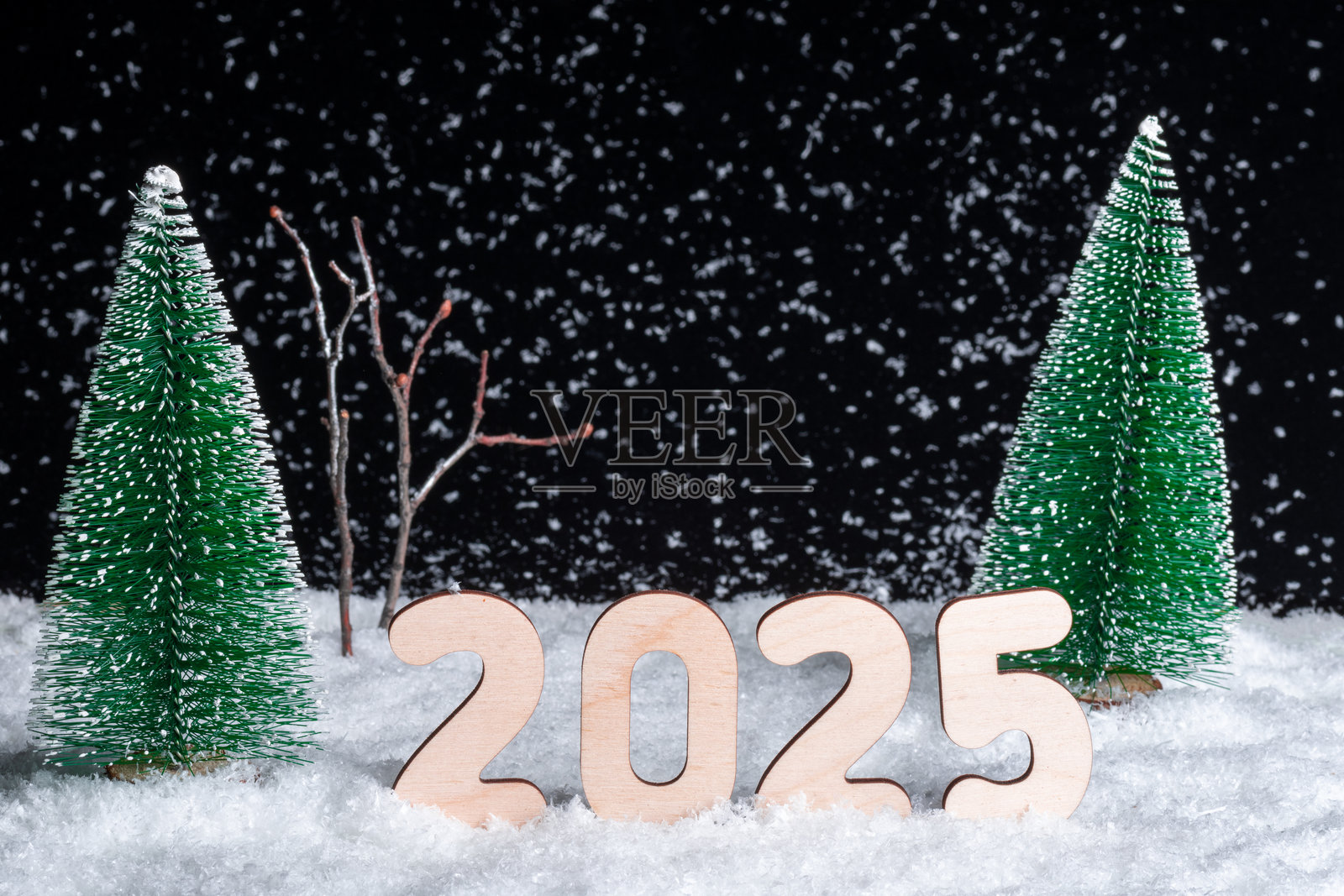 创意2025新年贺卡。2025的木制数字在雪花纷飞的森林中组成。照片摄影图片