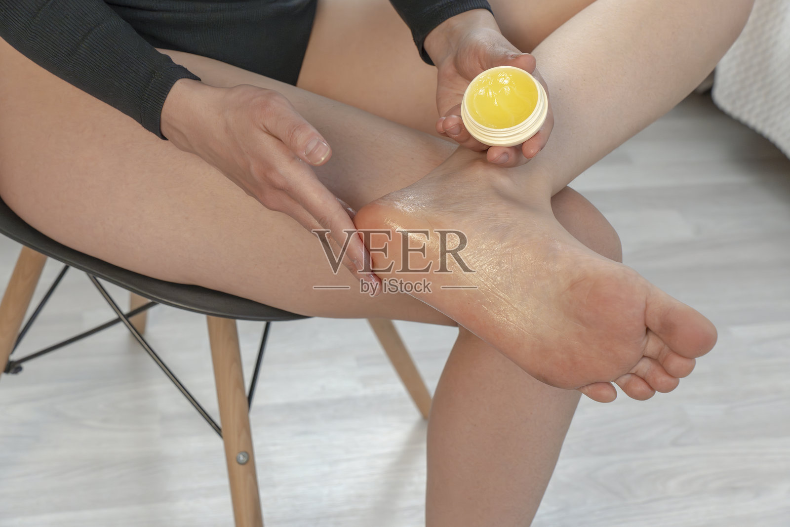 女孩在脚跟涂抹护肤霜。特写。足部皮肤护理照片摄影图片