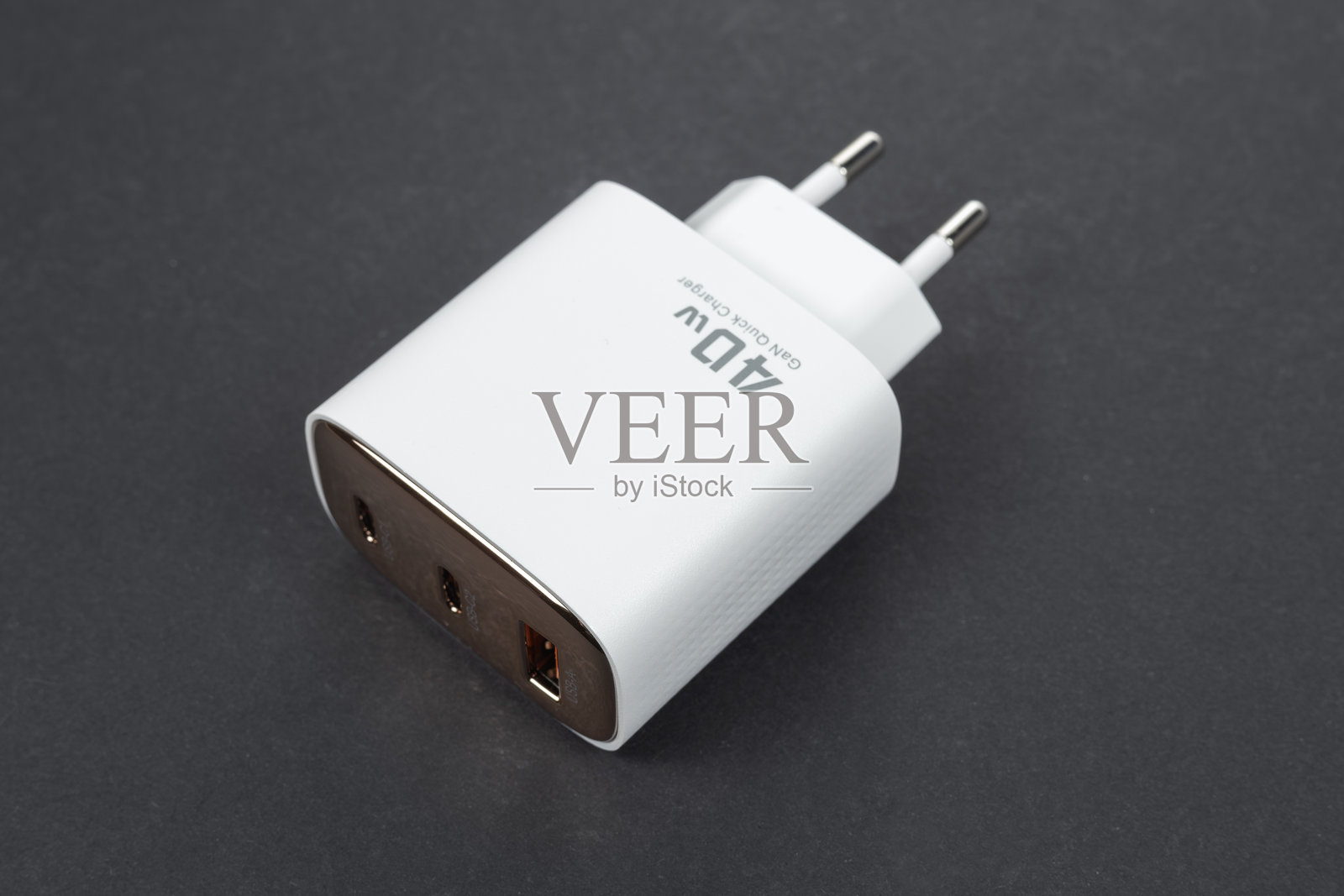 白色手机充电器放在灰色背景上。白色电压充电器用于手机和设备充电。智能手机充电器。照片摄影图片