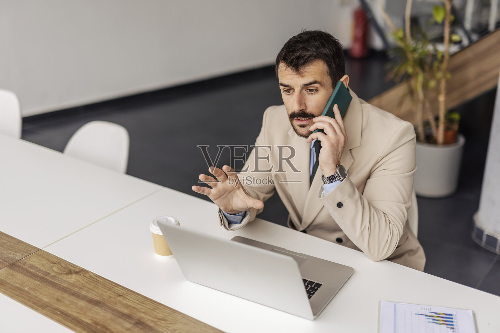 忙碌的商人在会议室里坐着，与客户通话的肖像。照片摄影图片