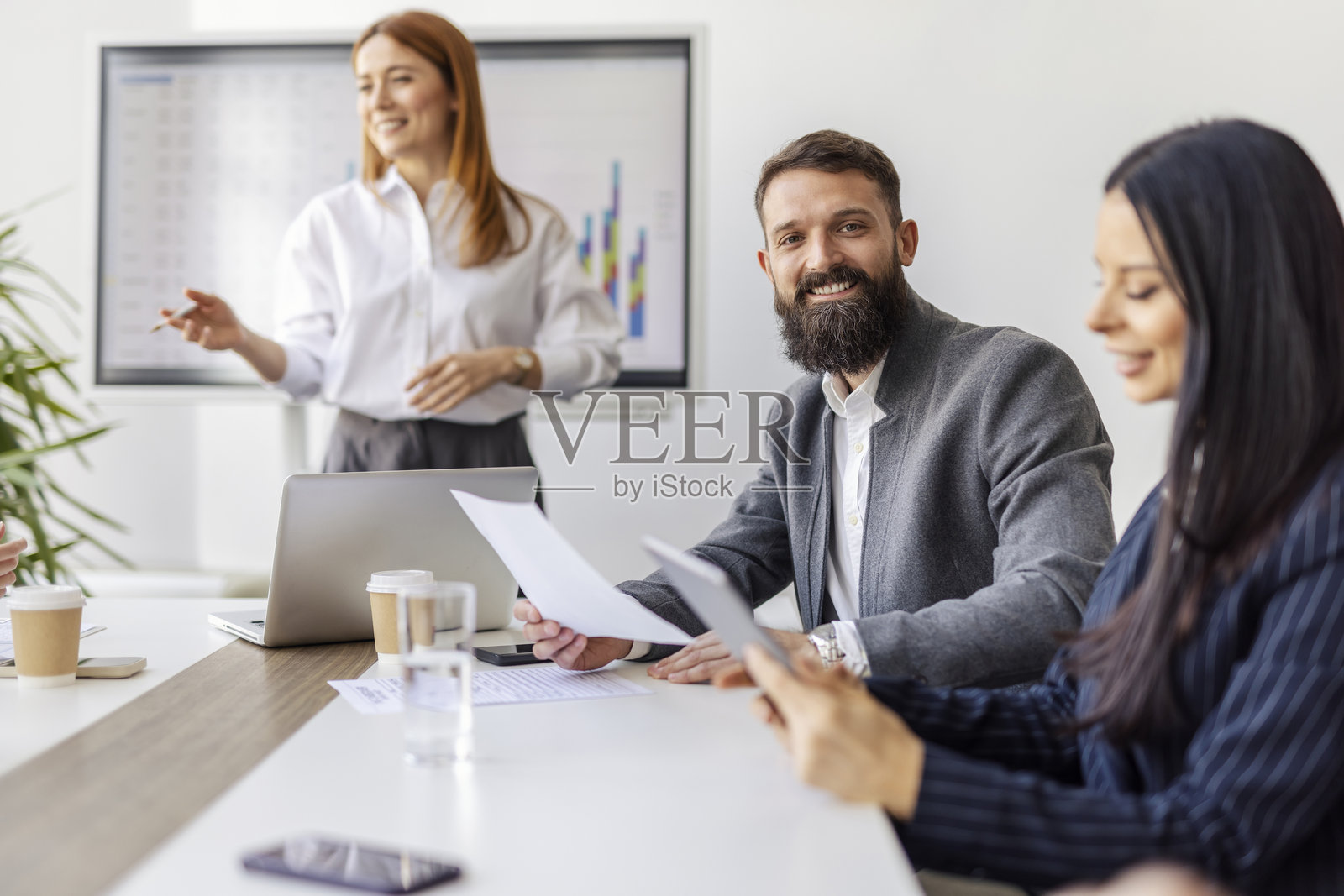 年轻商人在会议室里坐着，手中拿着报告和文件。照片摄影图片