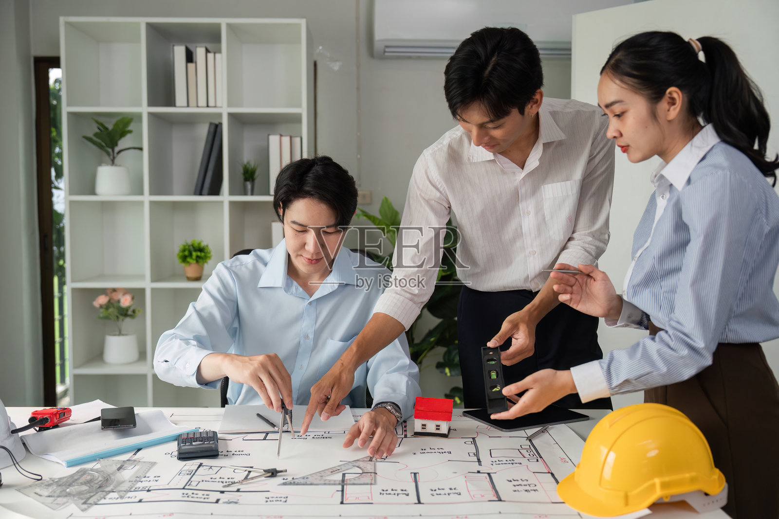 团队在桌子上评估项目细节，使用模型和蓝图进行协作设计会议和规划。照片摄影图片