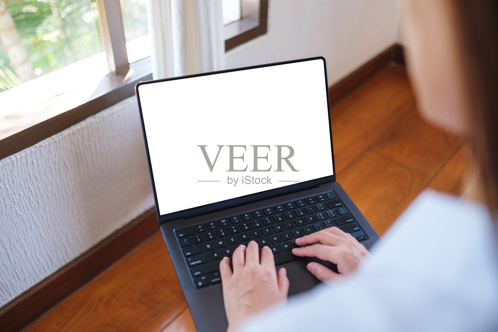 在家中，一位女性正在使用笔记本电脑打字，屏幕为空白的模拟图像照片摄影图片