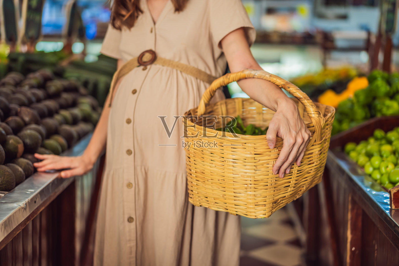 一位四十岁以上的孕妇在充满活力的有机市场上挑选有机蔬菜和水果，做出健康的选择，优先考虑自己的健康和宝宝的健康。照片摄影图片