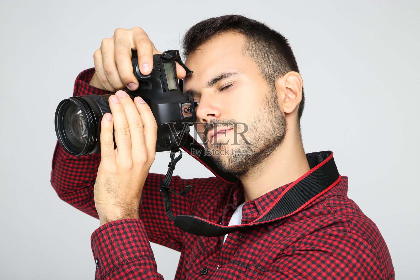 年轻摄影师在灰色背景下拿着相机照片摄影图片