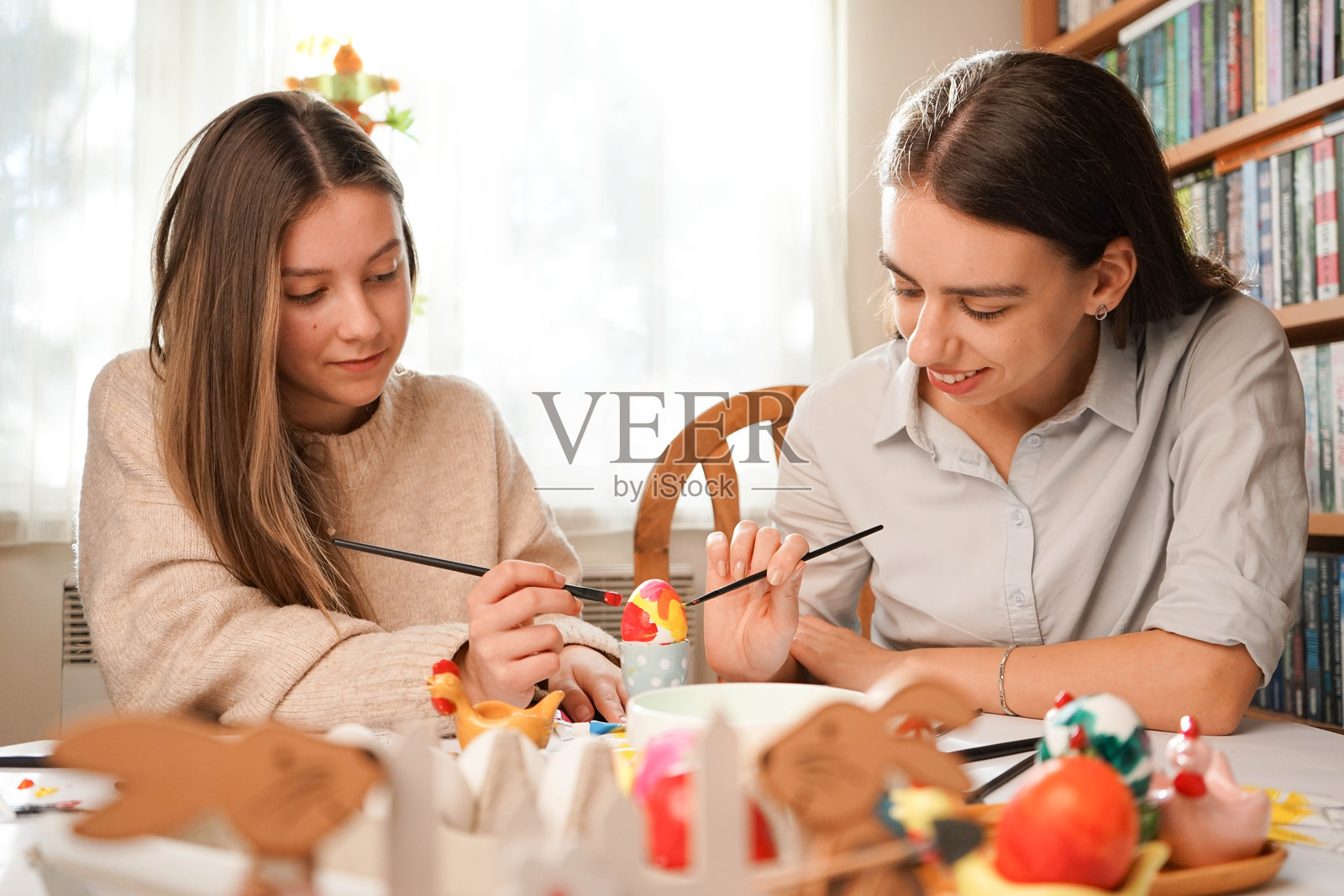 在阳光下：与朋友们快乐地装饰复活节彩蛋照片摄影图片