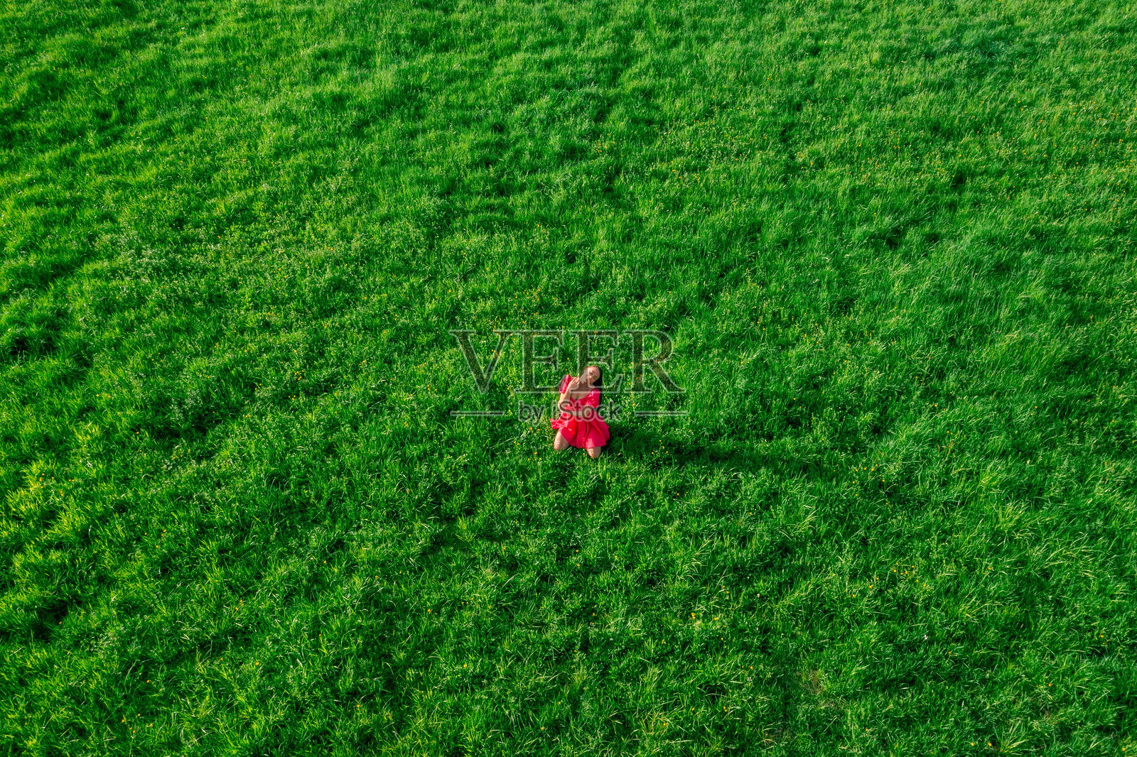 日落时分，女人坐在草地上的无人机视角照片摄影图片