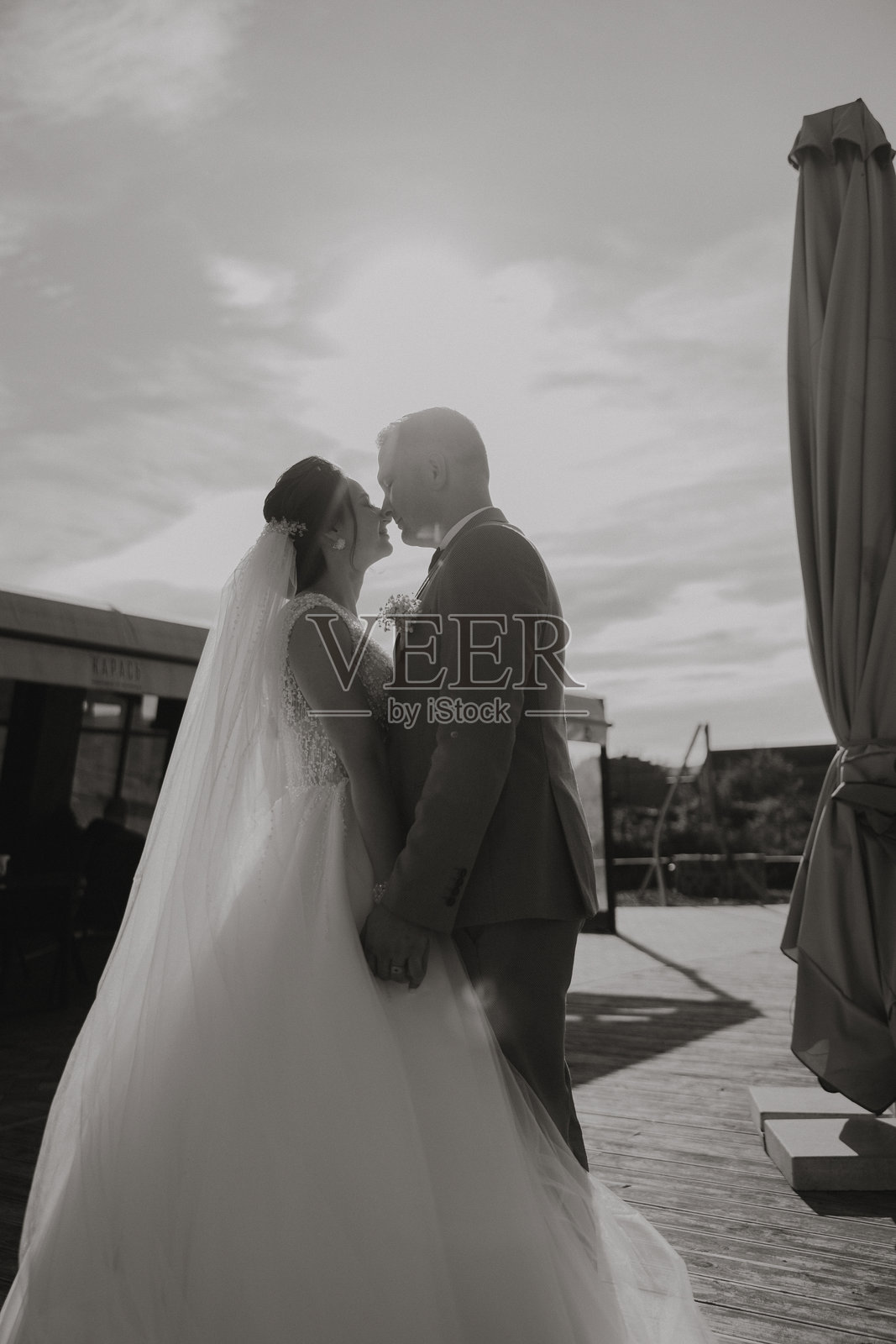新娘和新郎在木甲板上亲吻彼此照片摄影图片