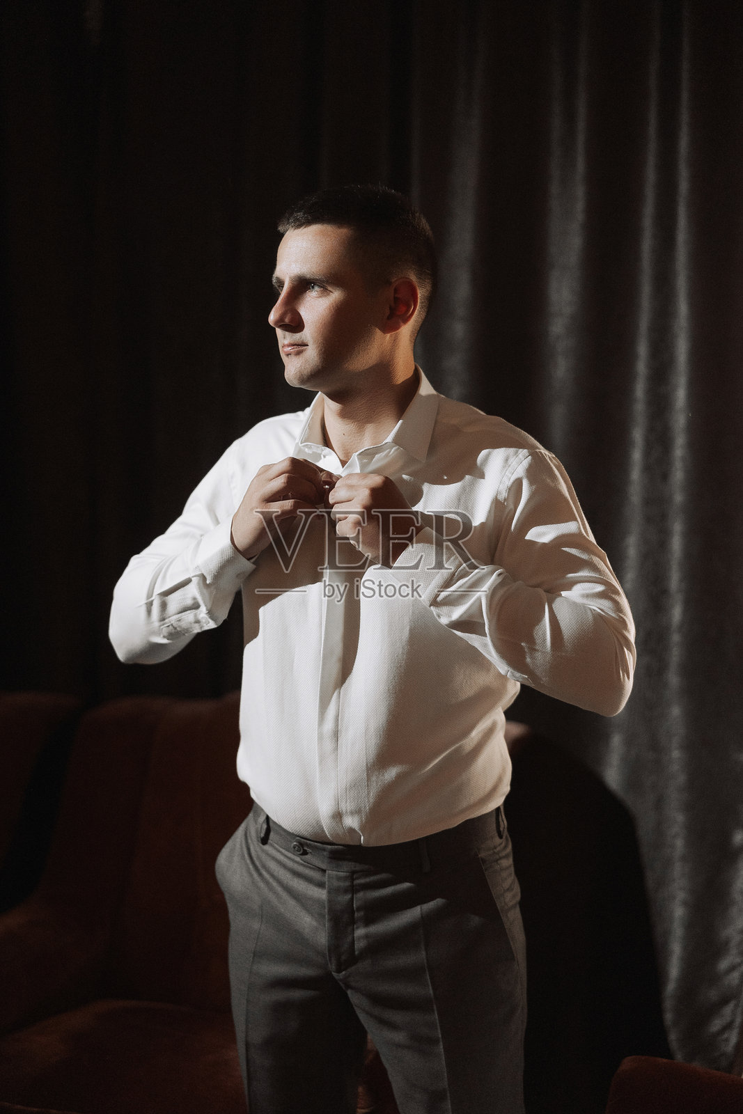 一名穿着白衬衫的男子正在穿衣服照片摄影图片