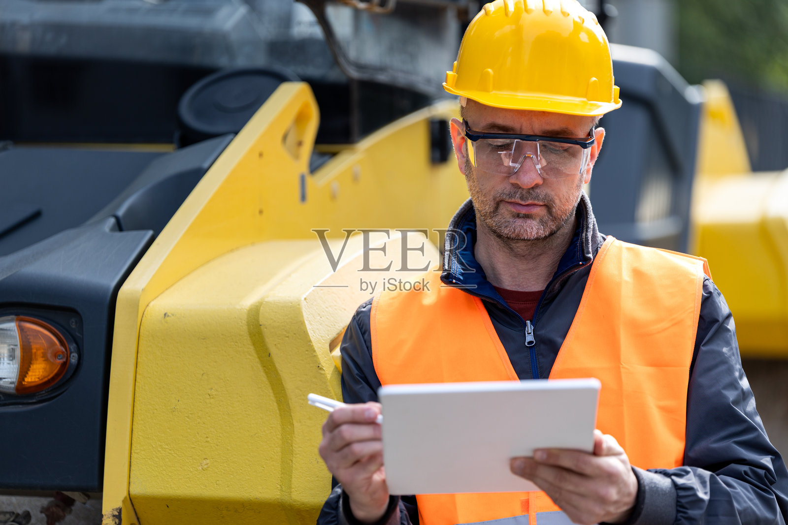 穿着安全装备的建筑工人在明亮的阳光下检查现场设备照片摄影图片