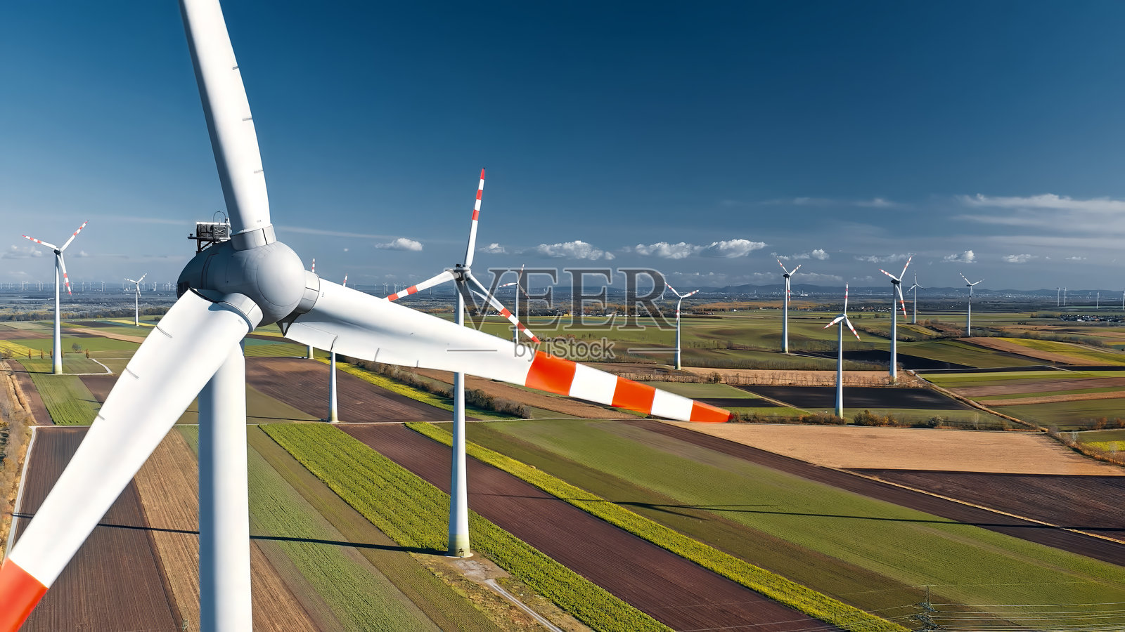 无人机特写风力涡轮机，背景是农业田野上的多个风力涡轮机照片摄影图片