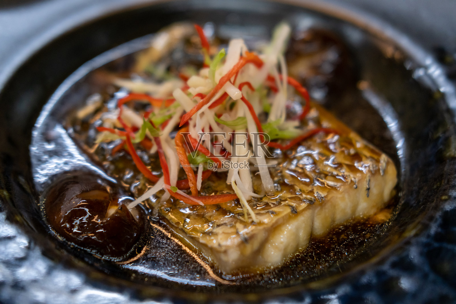 清蒸鲈鱼配酱油盛在盘子里照片摄影图片