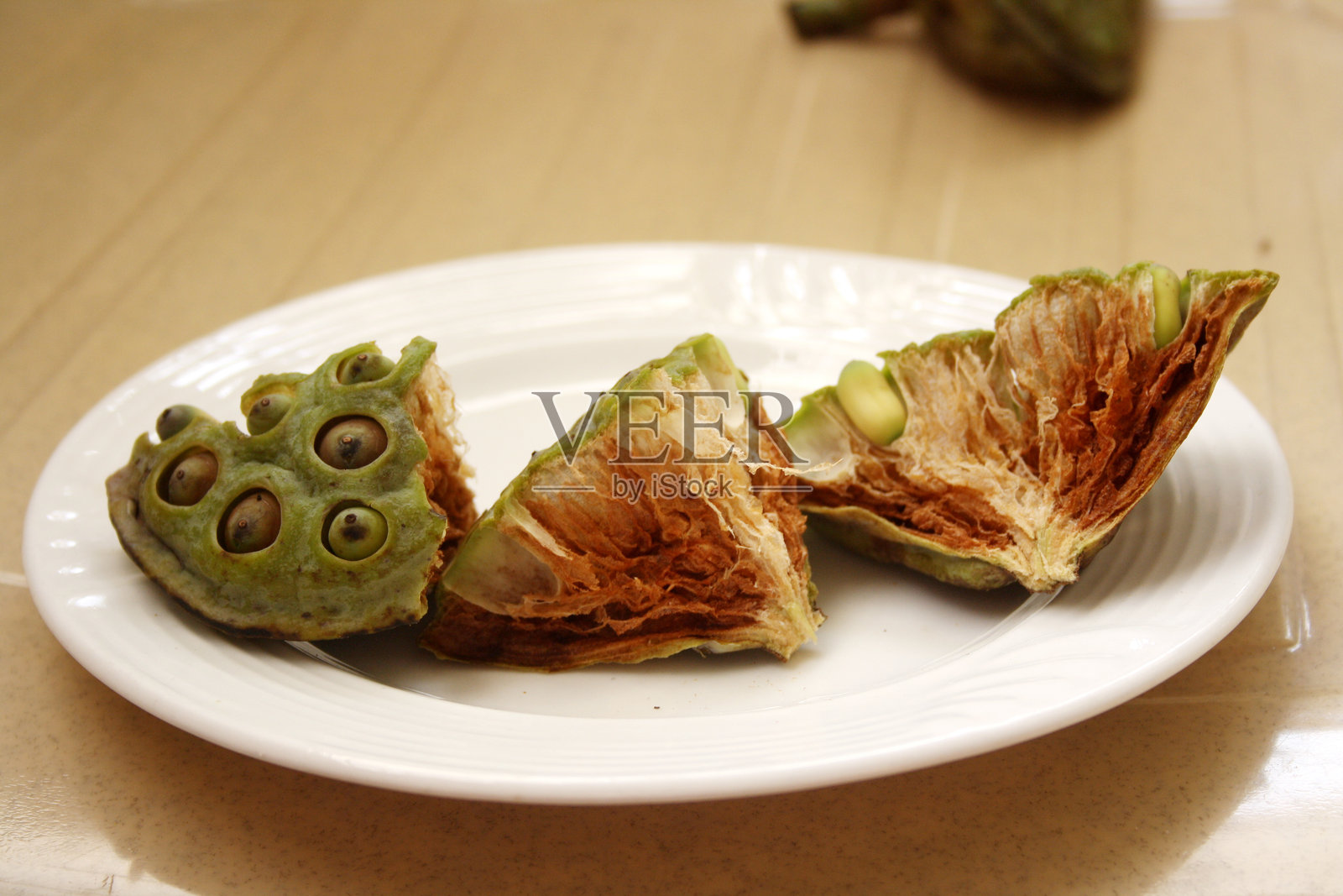 白盘中放置的印度莲（Nelumbo nucifera）种子头。照片摄影图片