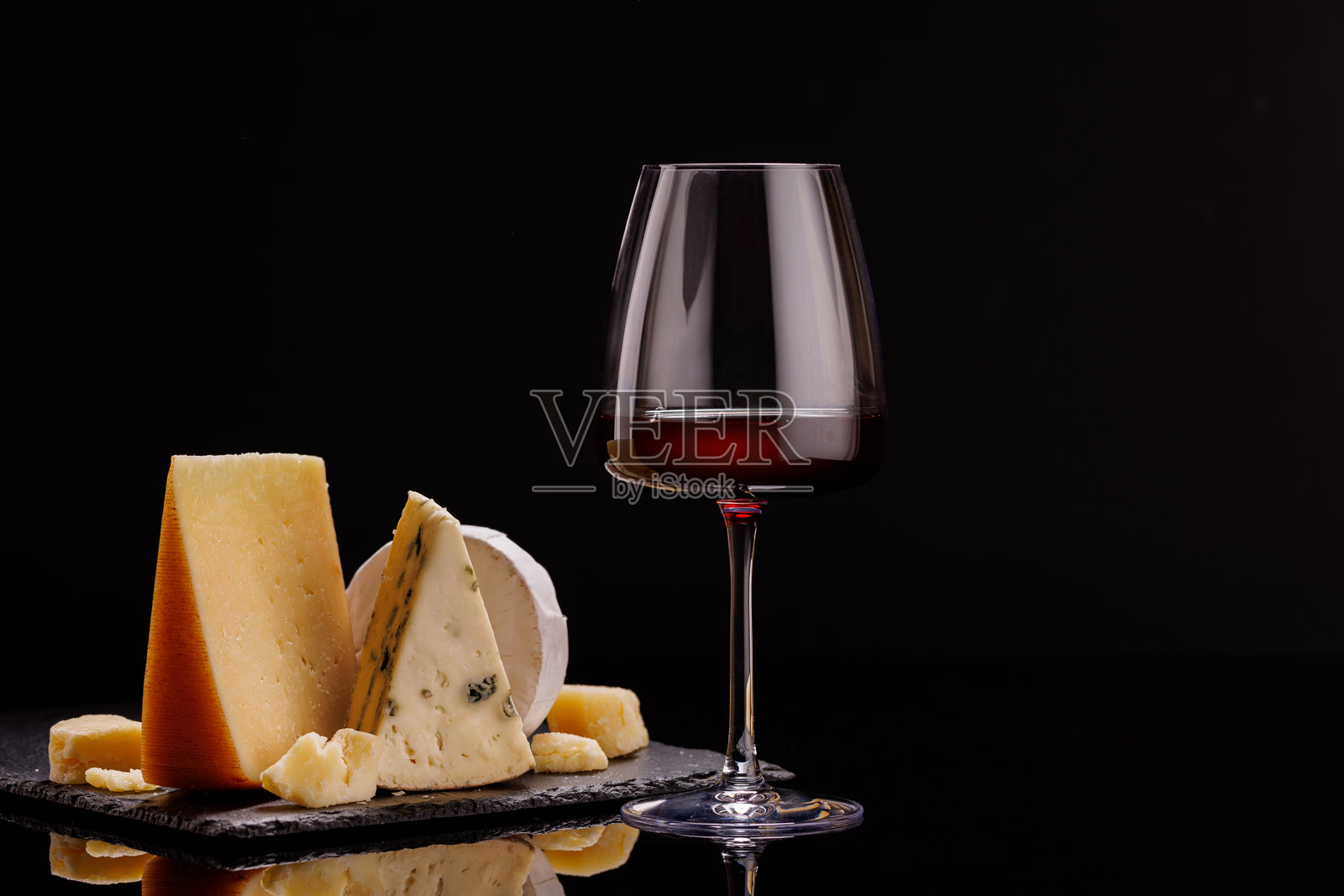 一盘精致的陈年奶酪，搭配酒杯。照片摄影图片