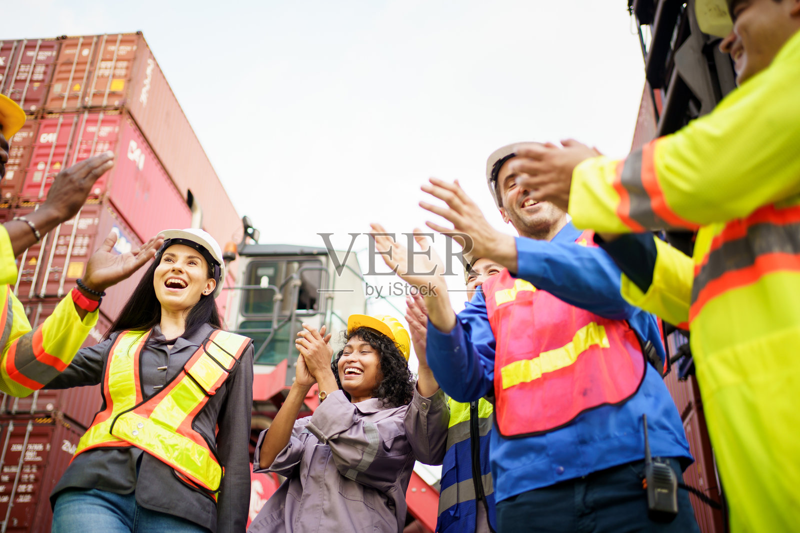 一群工程师和工人手握在一起，脸上洋溢着微笑，充满了成功的动力。照片摄影图片