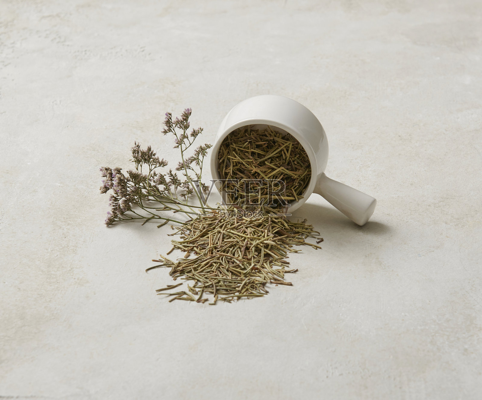 各种香草，如薄荷和百里香，摆放在装饰风格的桌子上，旁边有勺子、杯子和盘子，健康食品。照片摄影图片