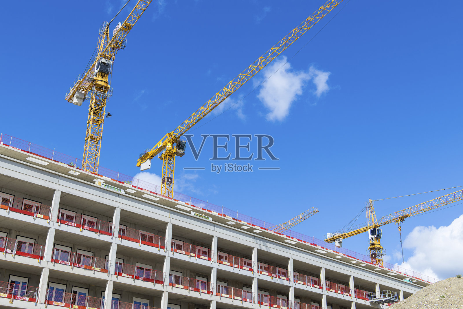 几台塔吊指向蓝天，位于建筑工地上。照片摄影图片