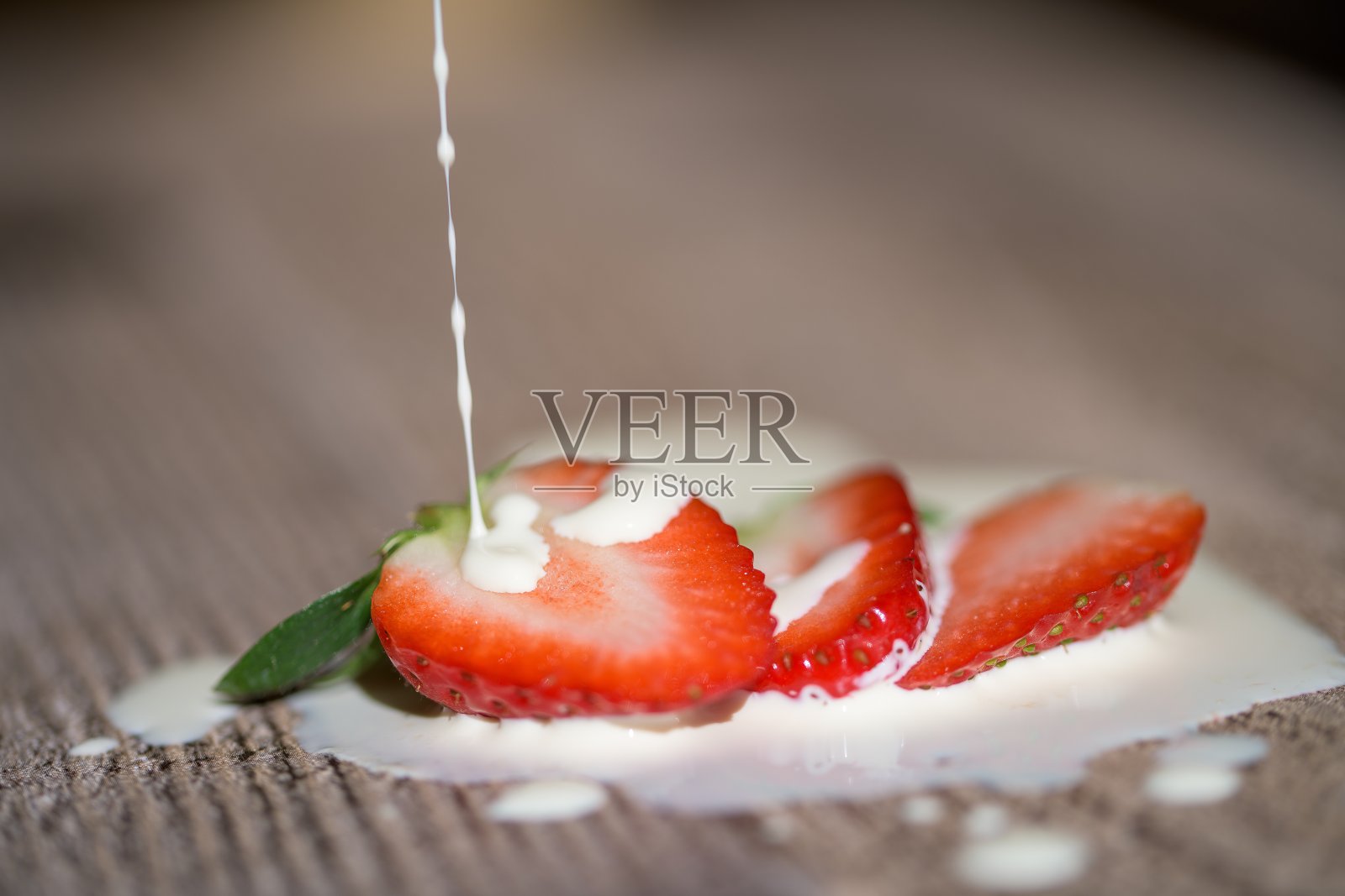 新鲜草莓切片上淋上新鲜奶油照片摄影图片