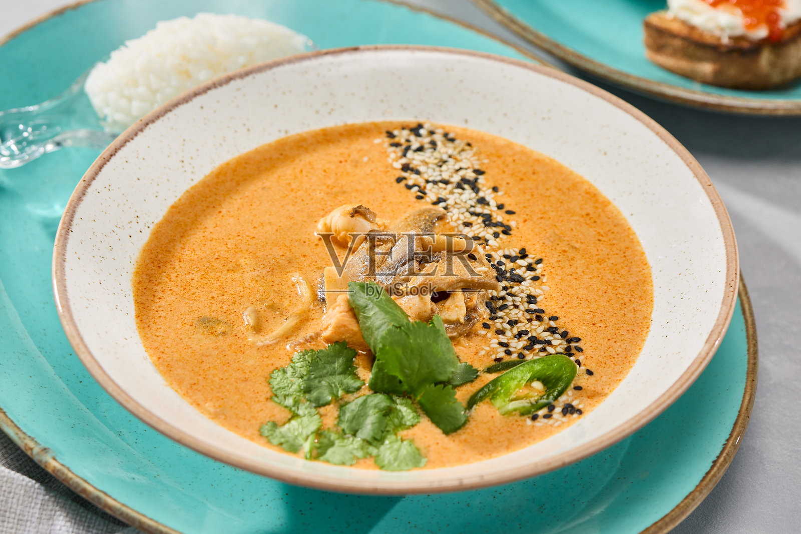 色彩鲜艳的冬阴功海鲜汤，配有丰富的装饰和新鲜的香草照片摄影图片