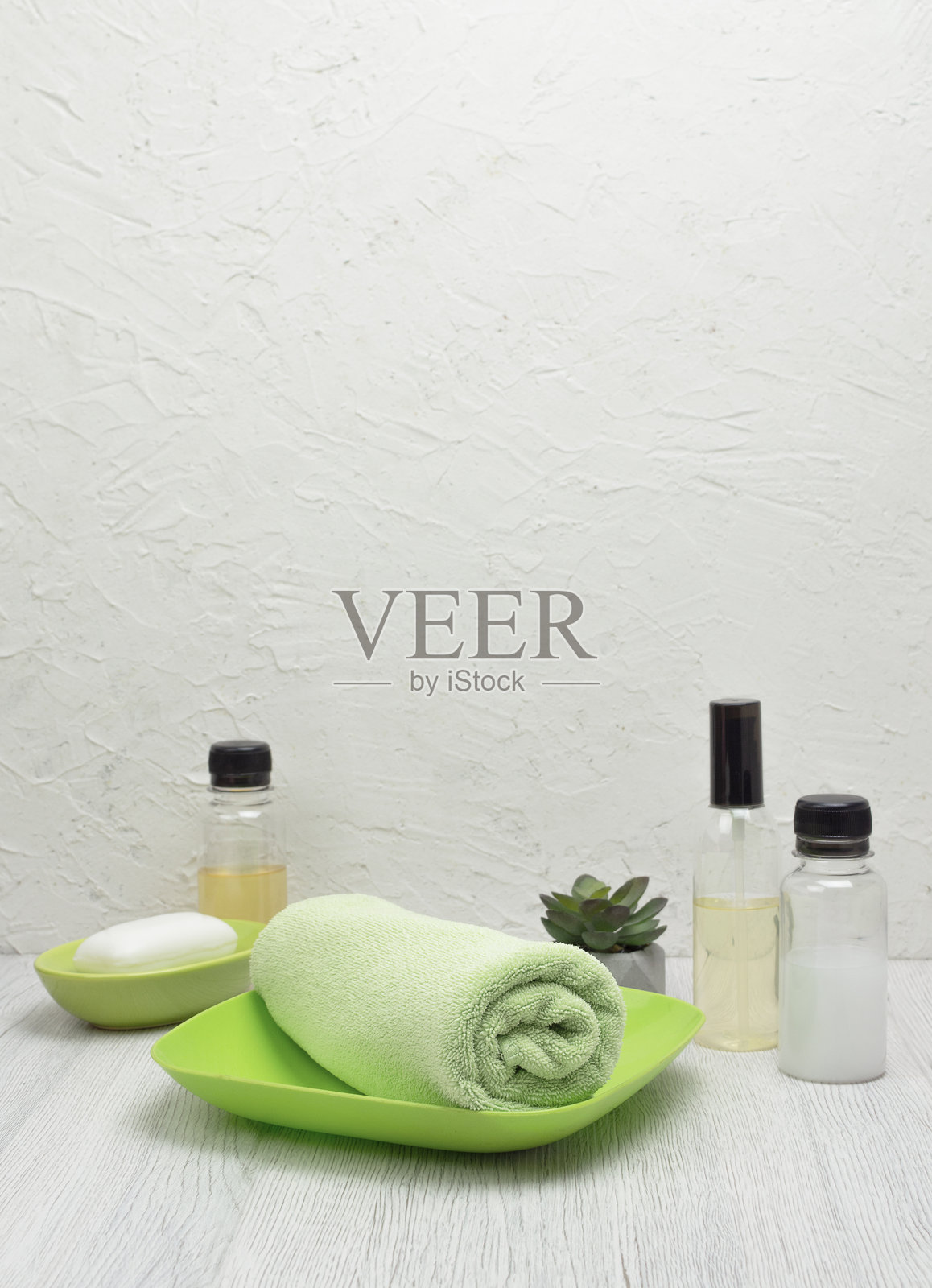 一条折叠的绿色毛巾上放着肥皂，背景为浅色，非常适合用于设计模型，留有空间用于文本和宣传内容。照片摄影图片