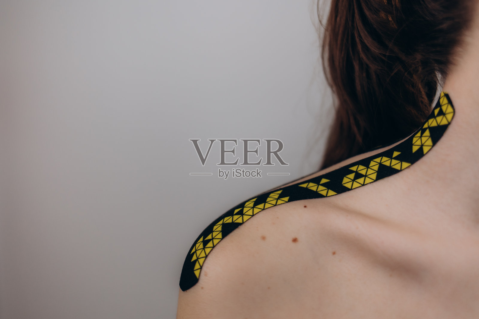 年轻女性穿着黑色运动服，肩膀上贴着运动疗法胶带的特写镜头照片摄影图片