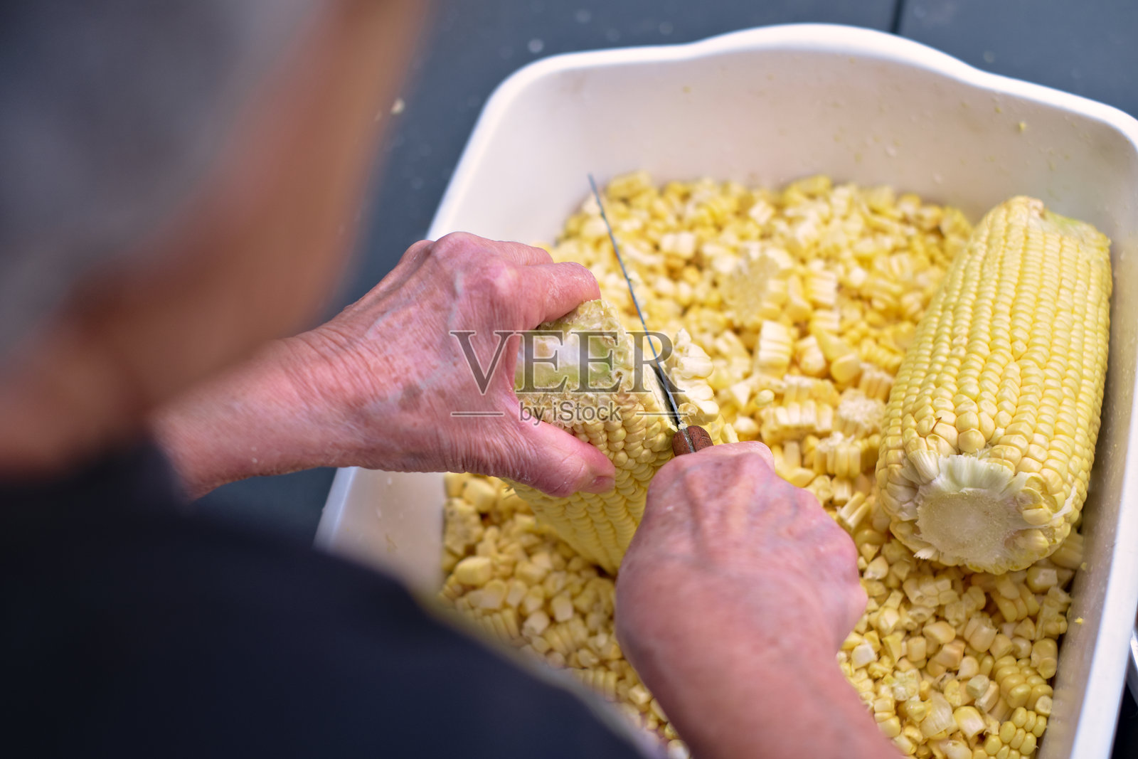 一个人用刀切玉米棒以准备蛋糕或玉米饼的照片照片摄影图片
