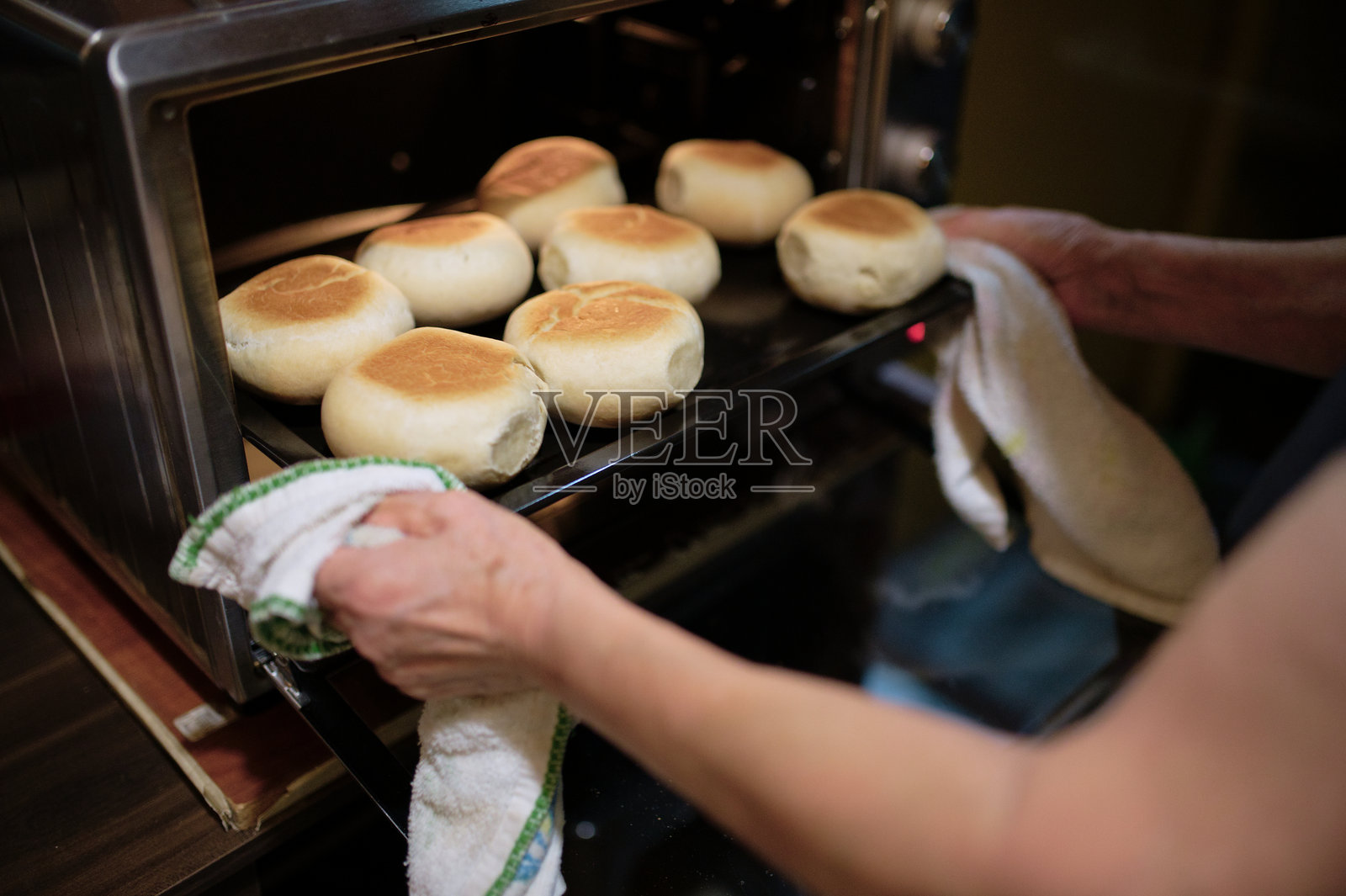 一位女性在揉面团以制作发酵面包，然后将其放入电烤箱中烘烤的照片照片摄影图片