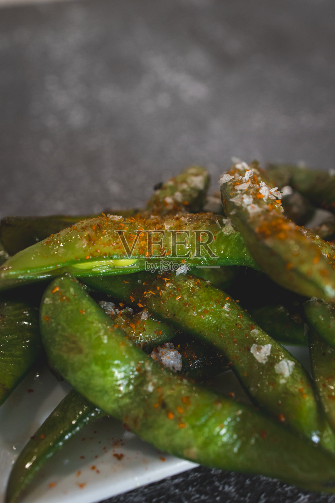 撒有辣椒片和海盐的香辣毛豆放在盘子里照片摄影图片