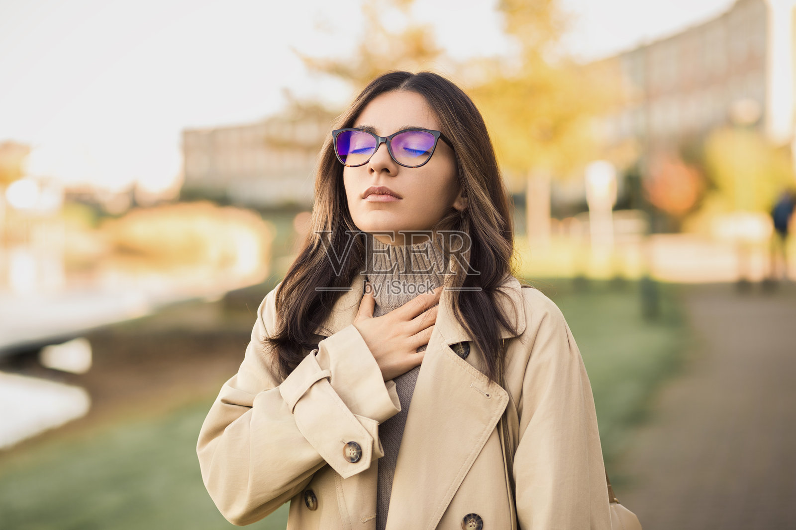 春天并不总是令人耳目一新。一位年轻女性在繁忙的街道上挣扎着呼吸，受到季节性过敏或城市污染的困扰。照片摄影图片
