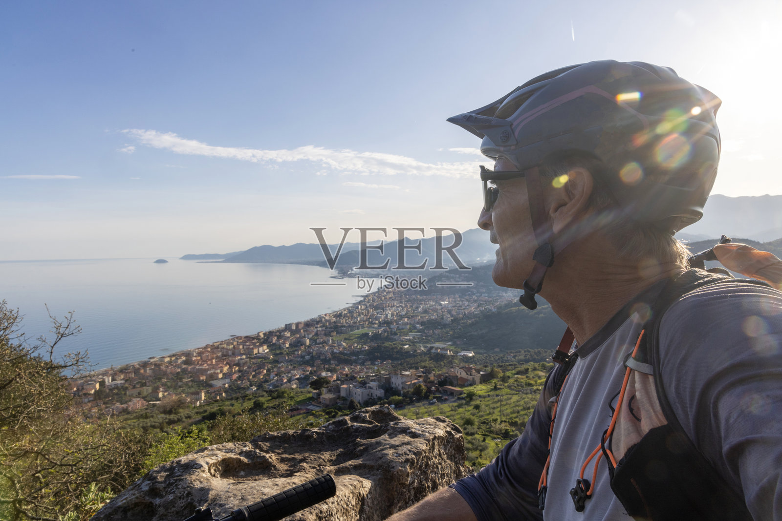 山顶骑山地自行车者的侧面视图，俯瞰海洋照片摄影图片