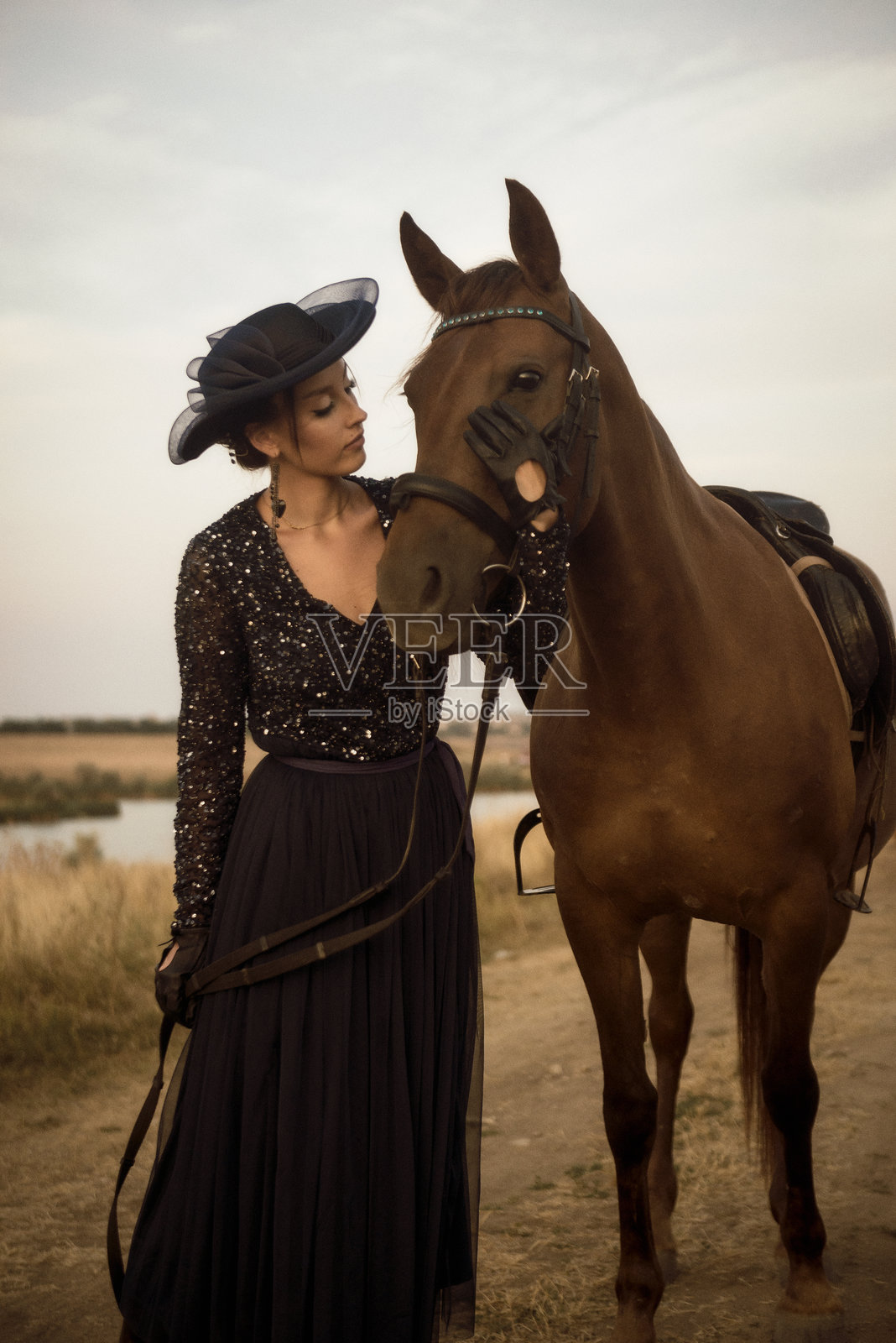 美丽的骑马女子在骑马后牵着马走。照片摄影图片