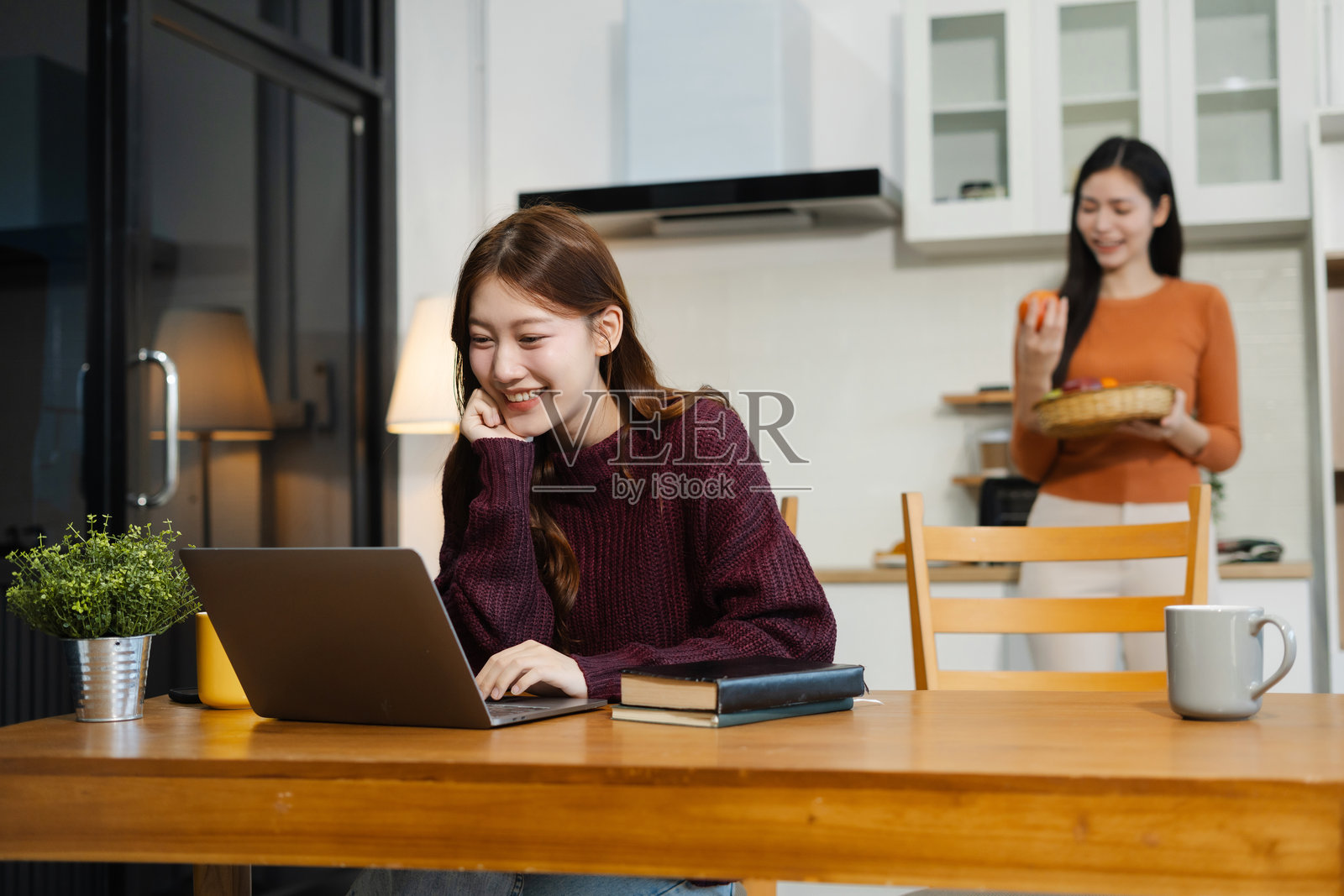 两位快乐微笑的女性在厨房里在线工作。照片摄影图片
