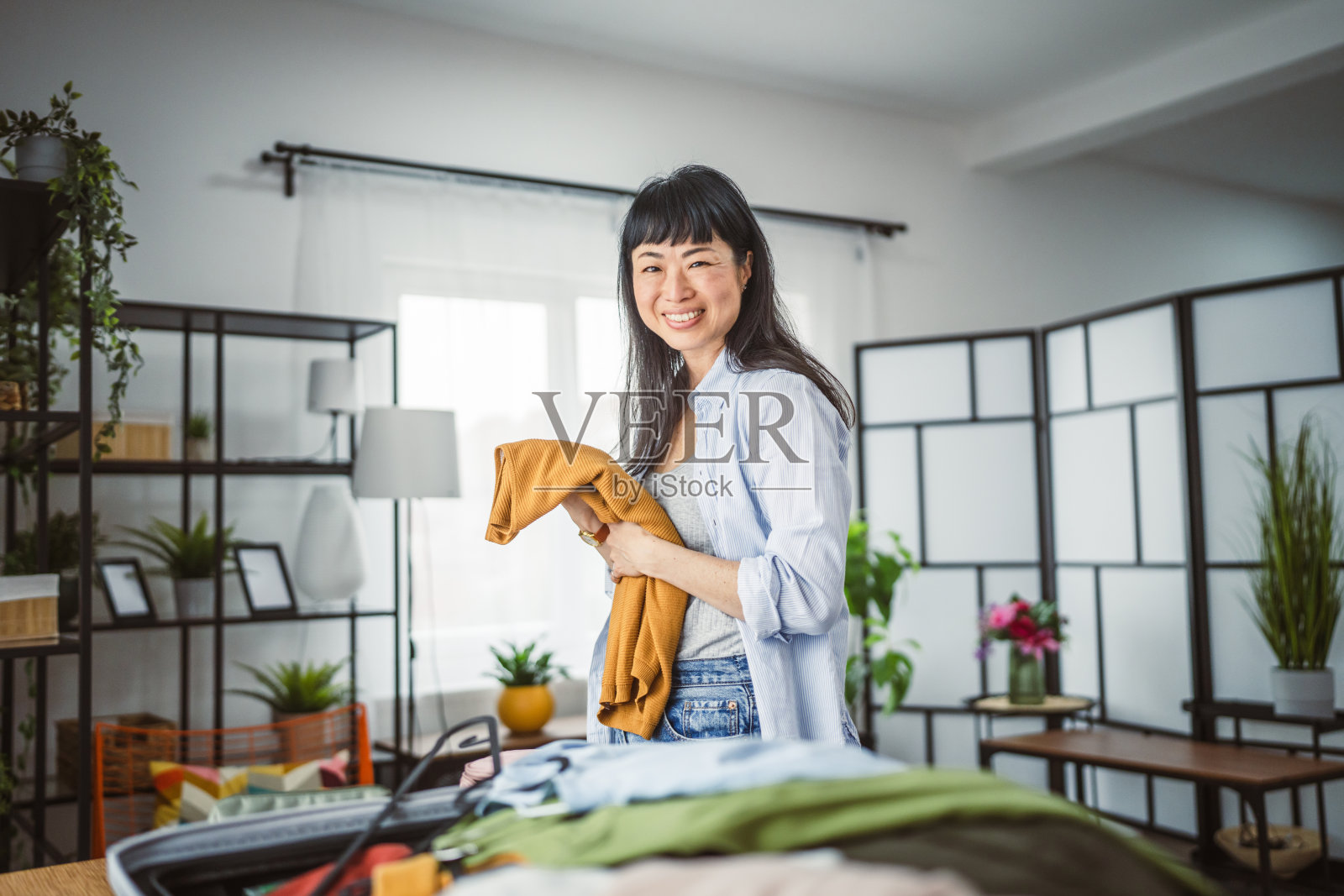 专注的日本女性在桌子上整理行李箱，为旅行做准备照片摄影图片