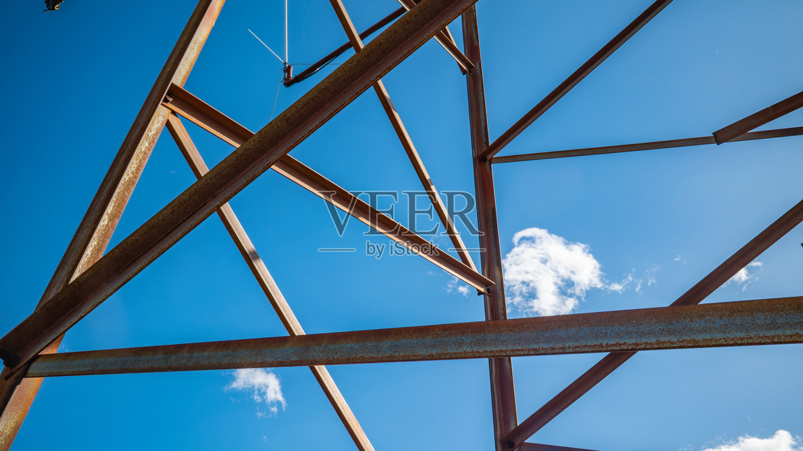 现代建筑工程展示：明亮蓝天与白云下的工业钢框架结构，带有几何图案。照片摄影图片
